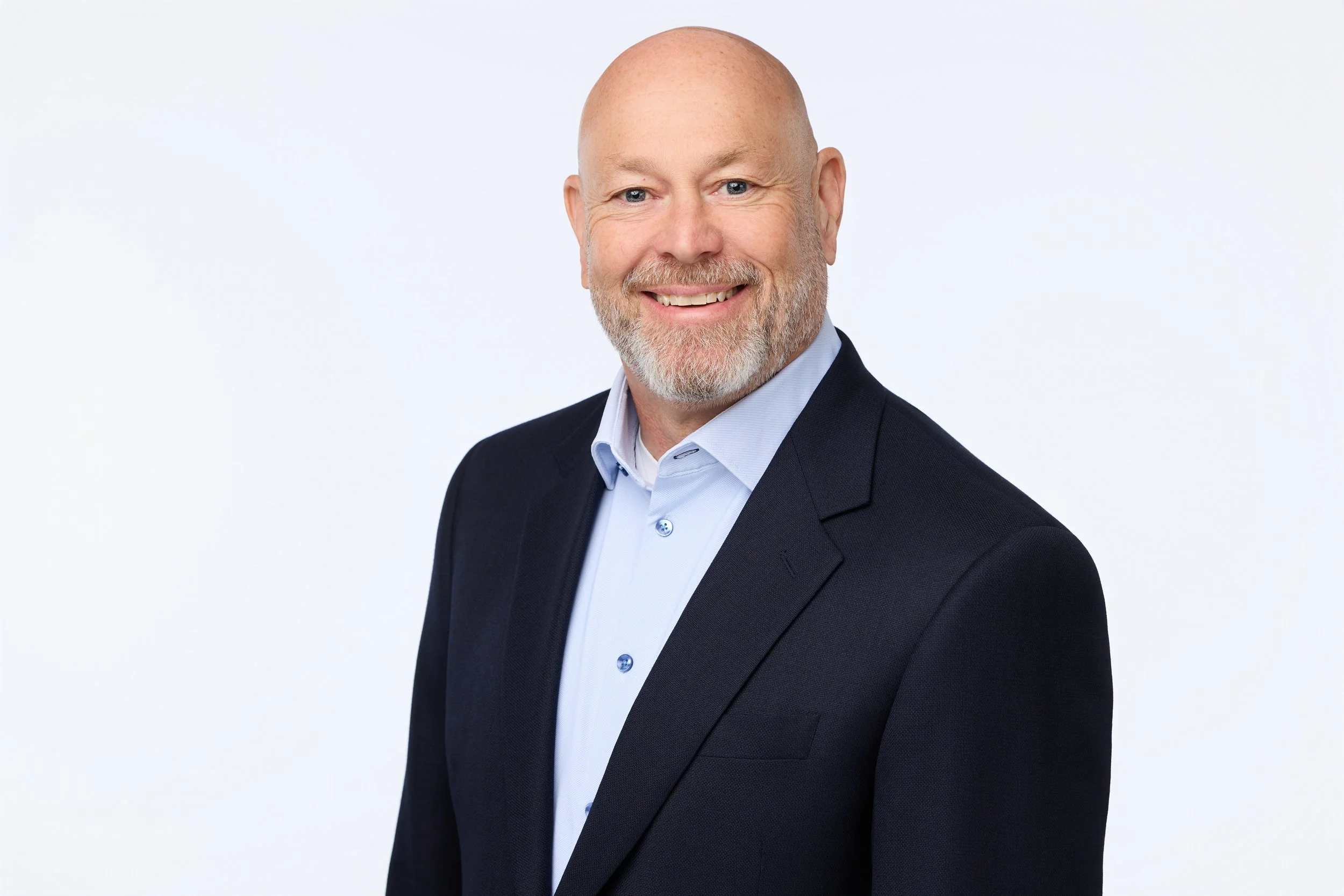 Professional headshot of a smiling bald man in a business suit.