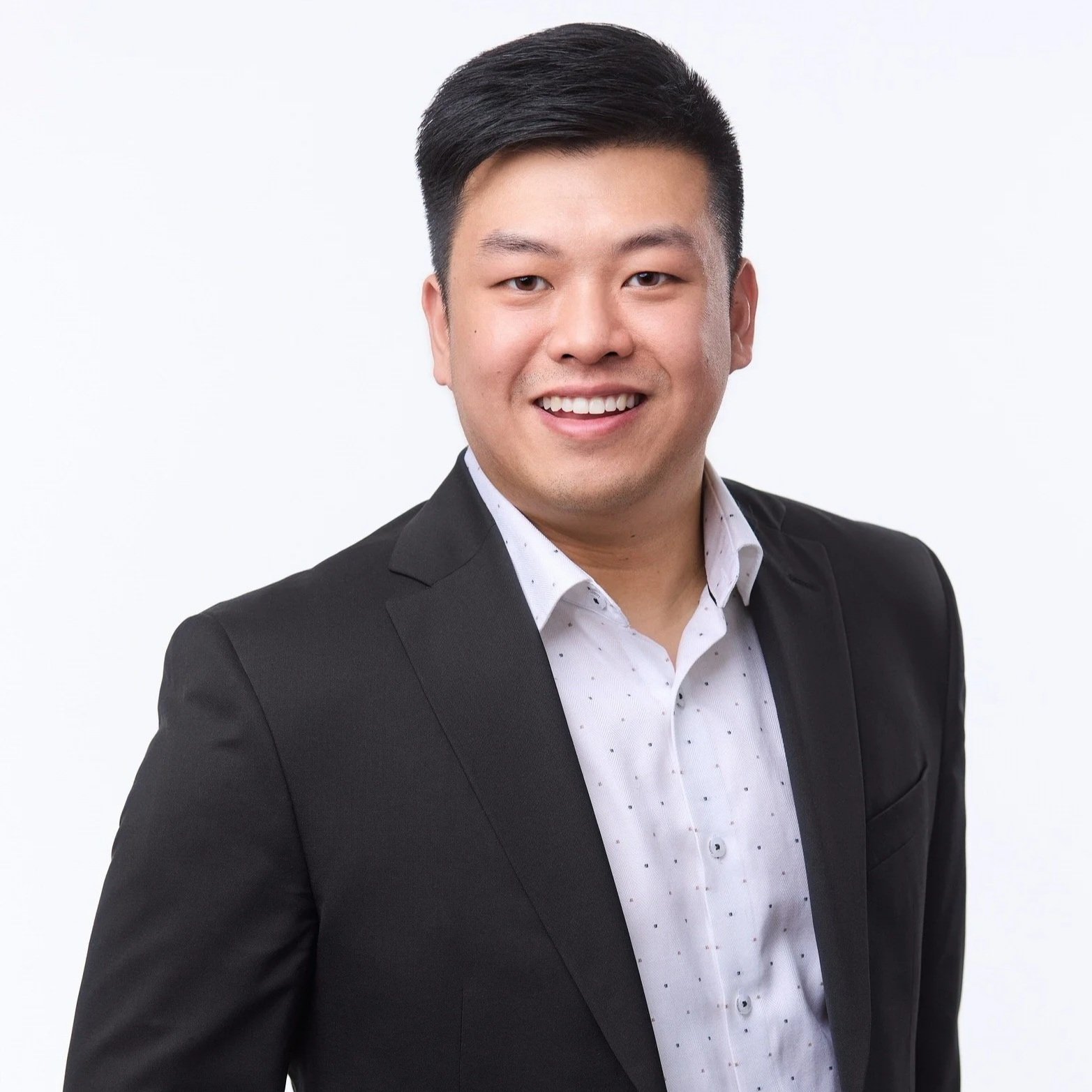 Professional corporate headshot of Alan in a dark suit against a bright white background.