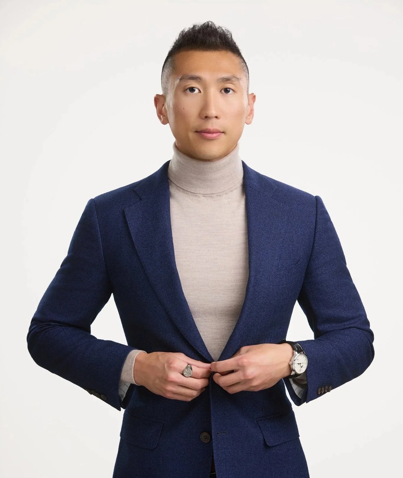 Full-length executive portrait of a man in a navy suit against a bright white studio background.