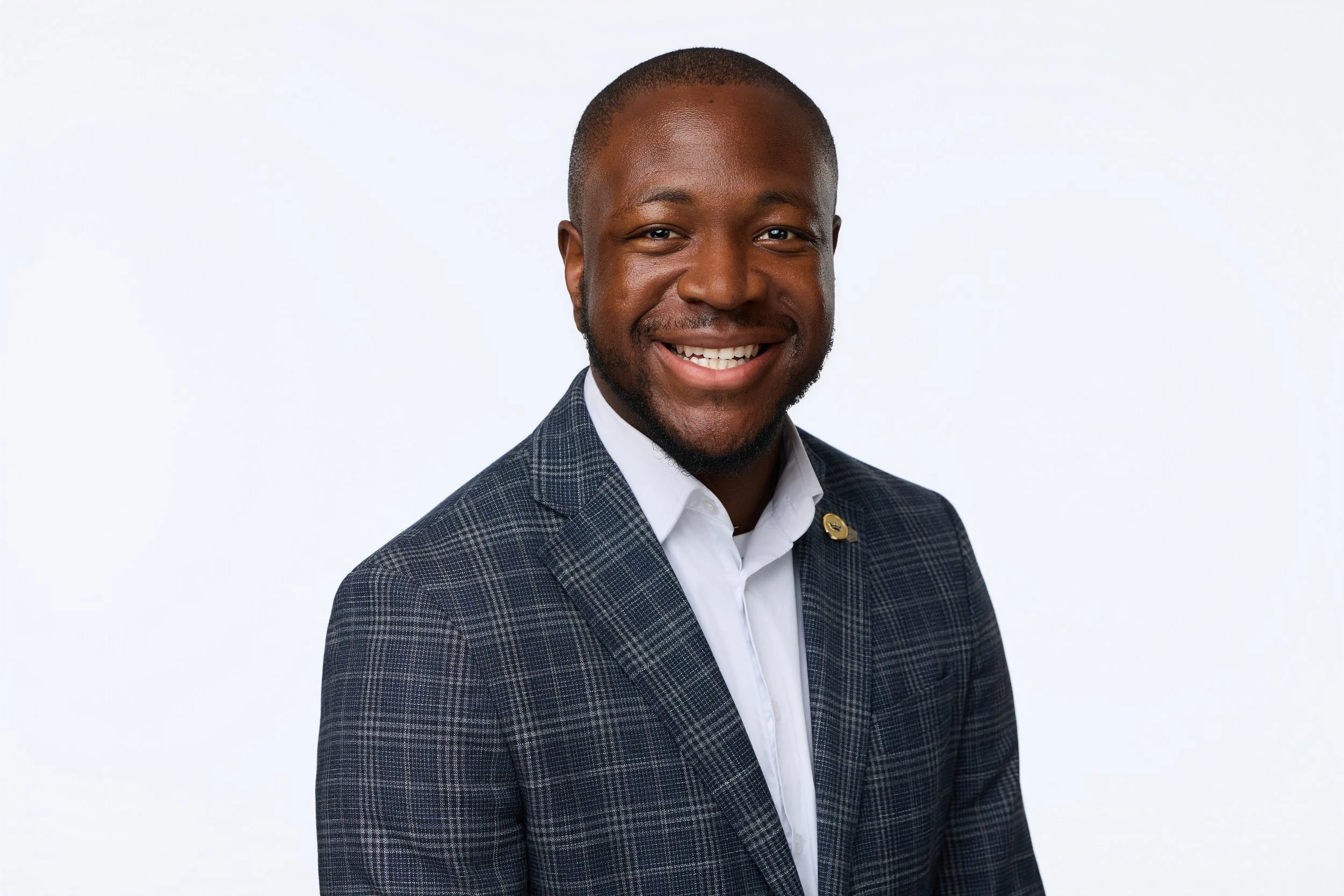 Business portrait of a Black man in corporate attire smiling at the camera.