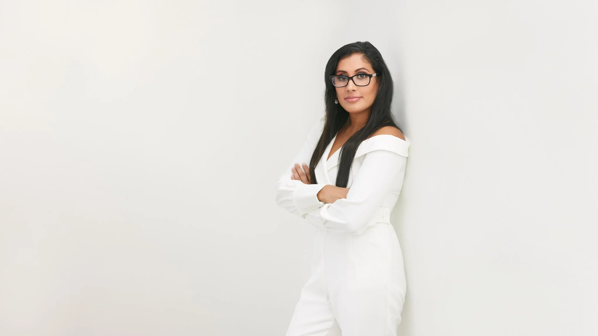 Modern business portrait of a woman in a white suit against a bright studio background.