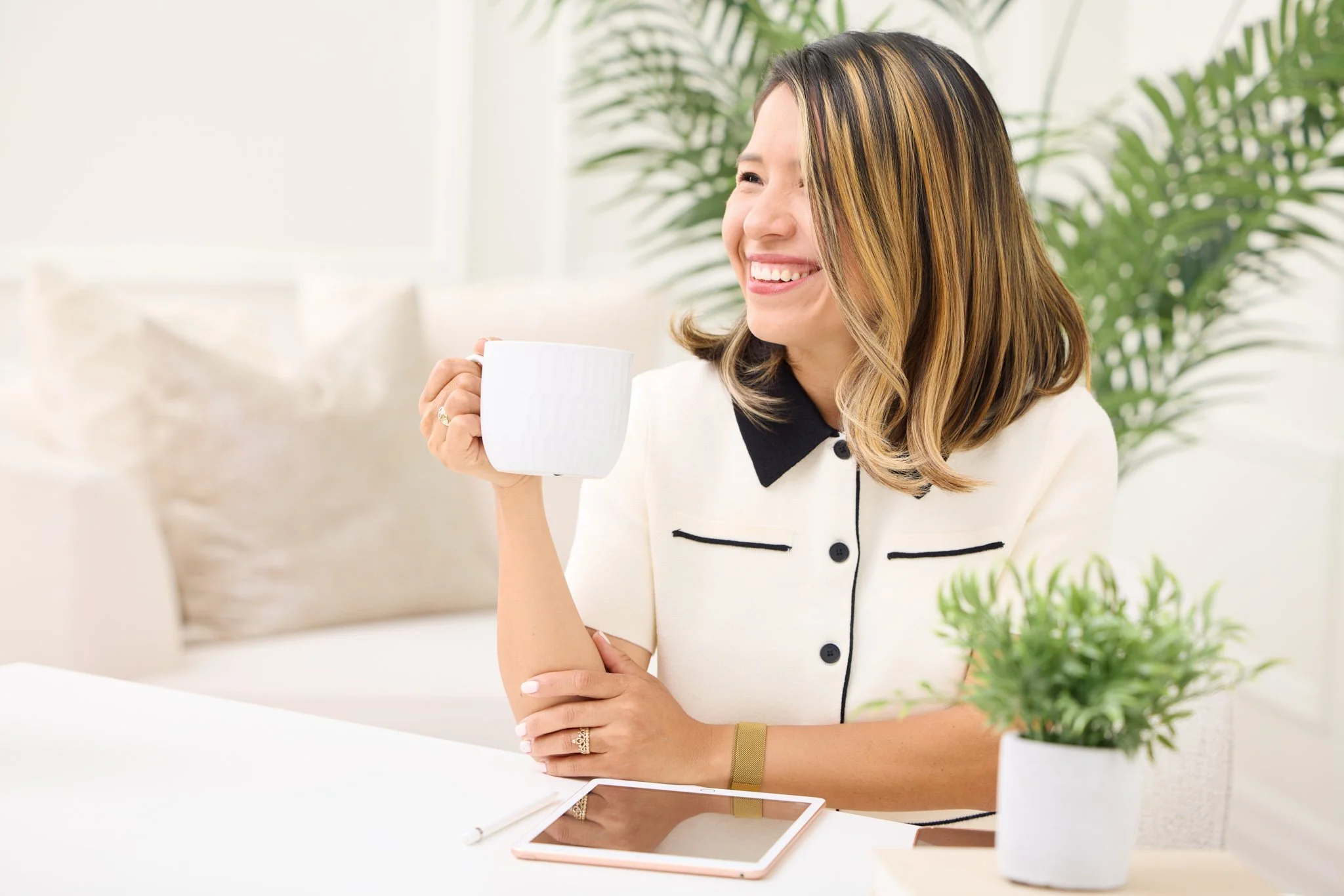 Woman smiling with a coffee mug at a desk during a lifestyle branding photography session.