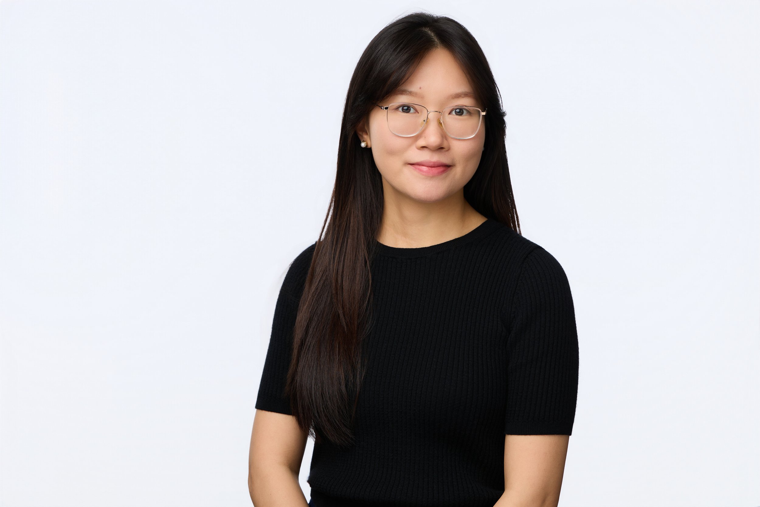 Business portrait of a dark-haired woman wearing wire glasses with a relaxed smile.