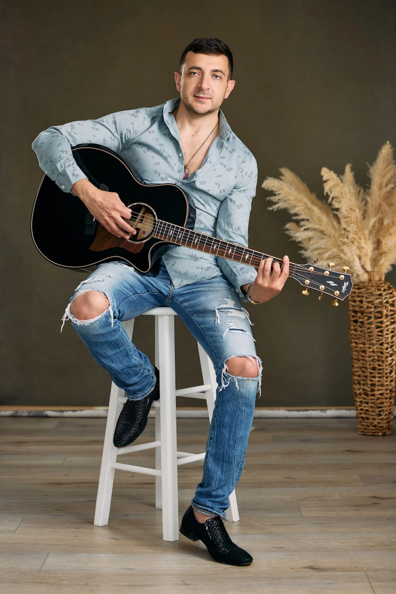 Creative professional branding portrait of a musician seated with an acoustic guitar.