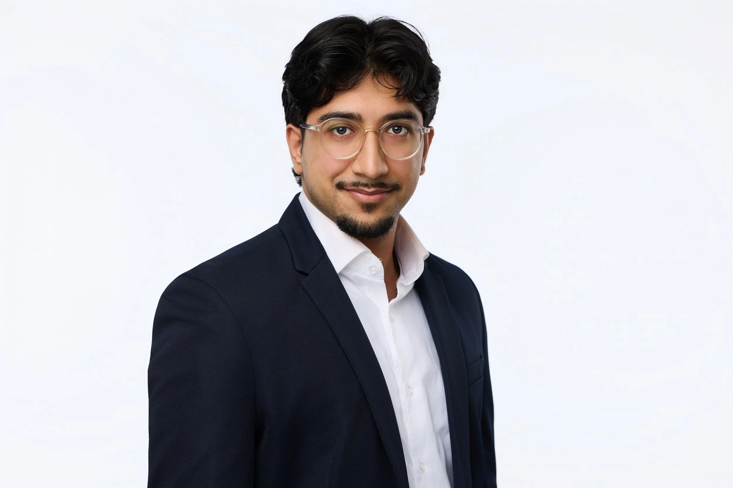 Corporate portrait of a man with glasses in business clothing.