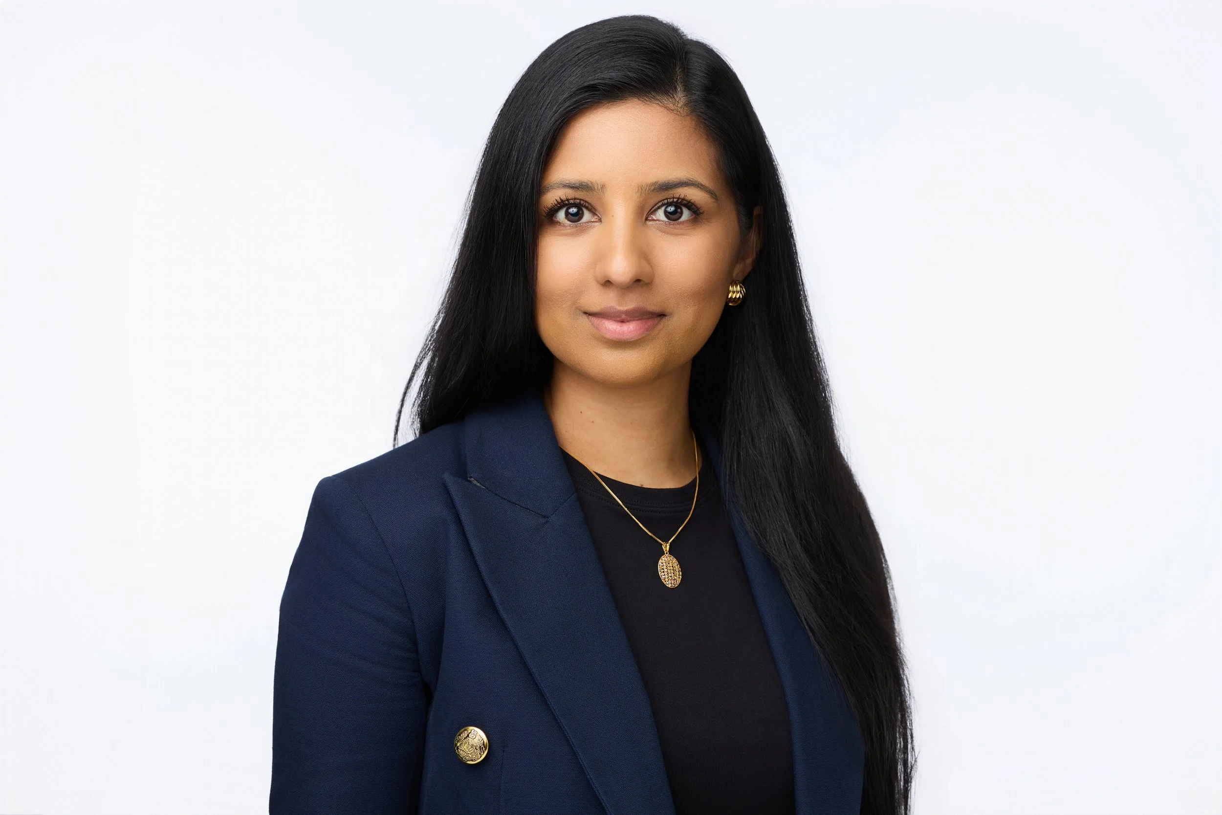 Professional portrait of a dark-haired woman against a clean studio background.