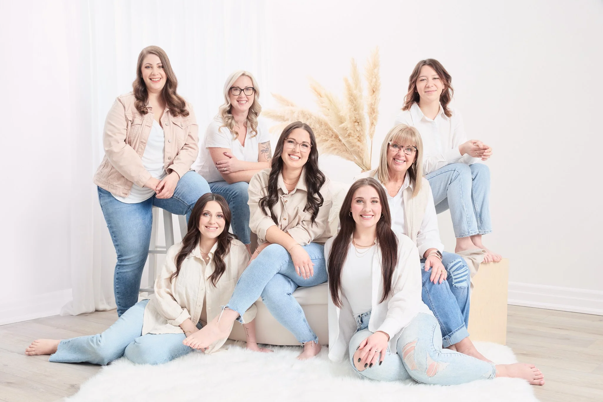 Seven women from Allure Hair and Makeup posing together in coordinated white tops and blue jeans.