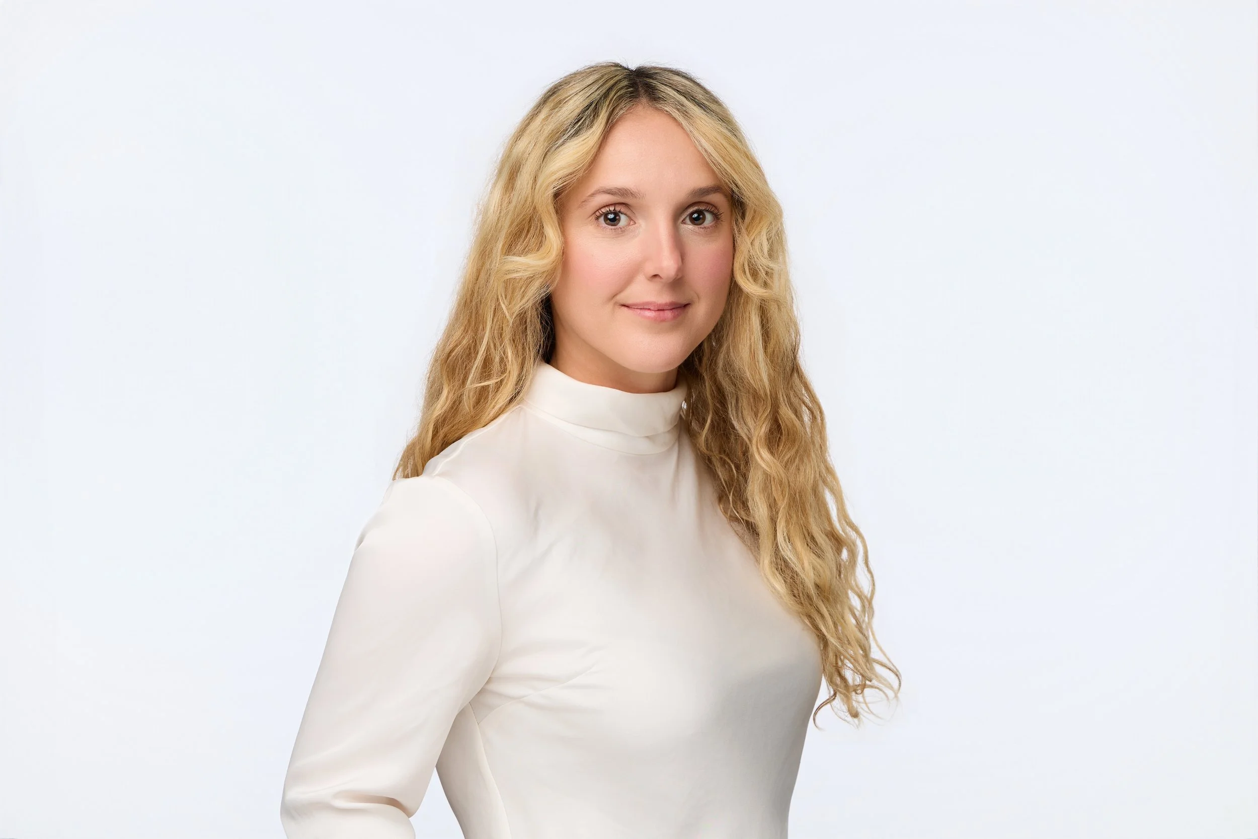 Studio headshot of a blonde curly-haired woman with soft lighting.