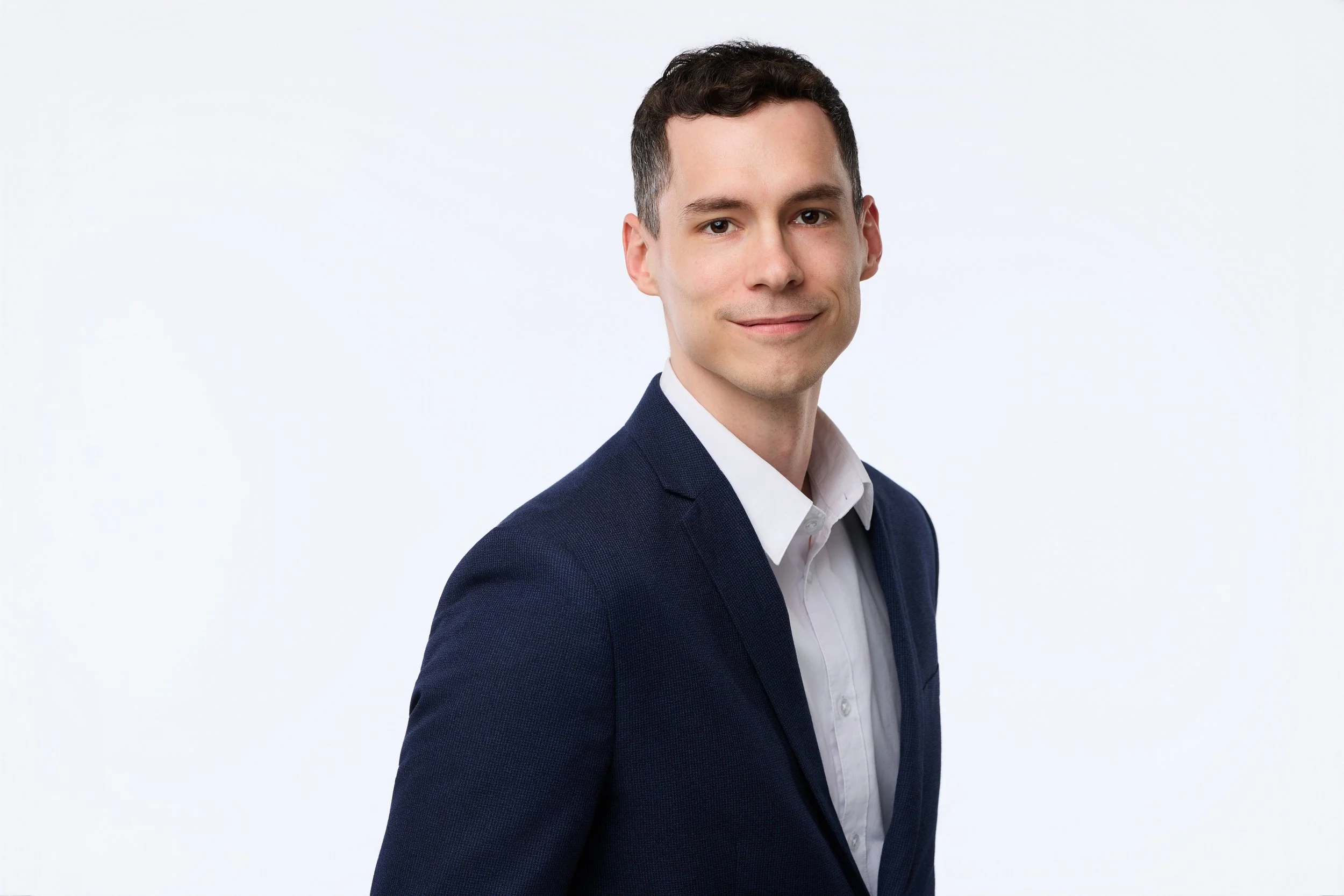 Corporate headshot of a man in a navy business suit smiling at the camera.