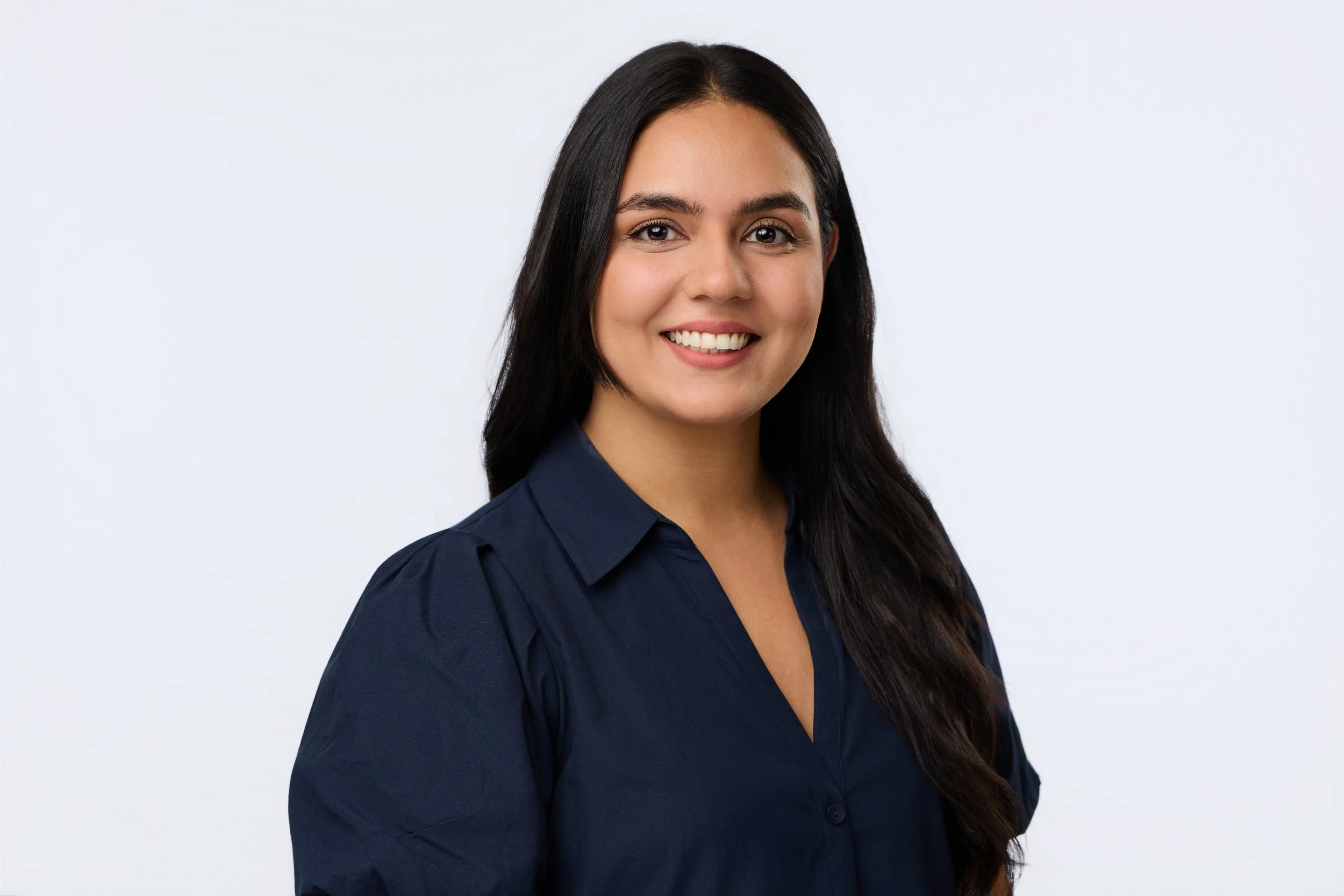 Corporate portrait of a smiling dark-haired woman in professional attire.