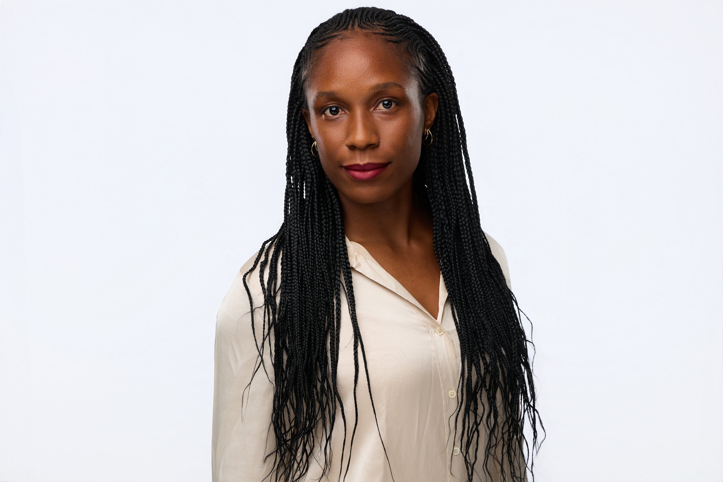 Professional headshot of a dark-haired woman in an ivory blouse against a clean white backdrop.