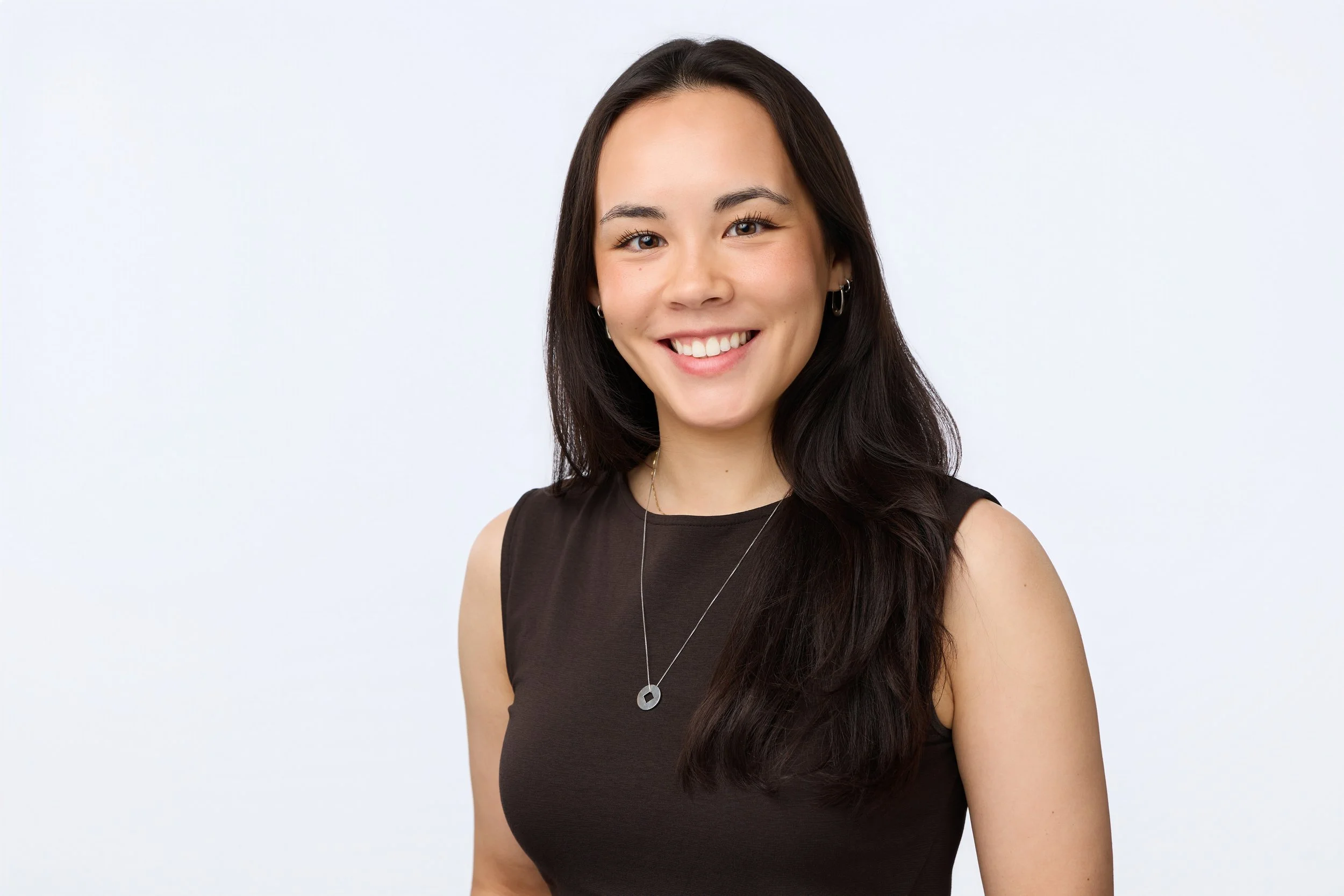 Business headshot of a smiling woman wearing a brown dress.