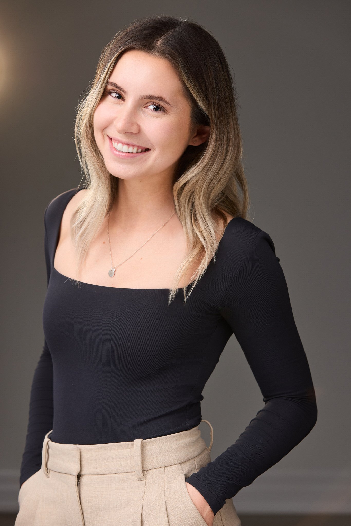 Professional branding portrait of Ashley in a black top against a dark neutral background.