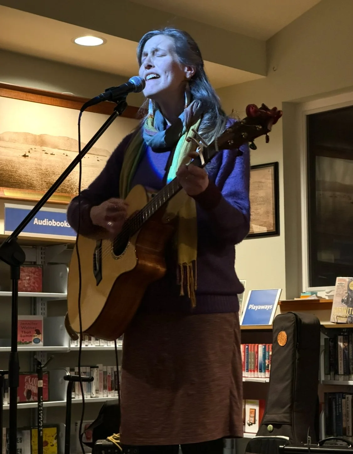 Singer-songwriter Amanda West performing live with acoustic guitar.
