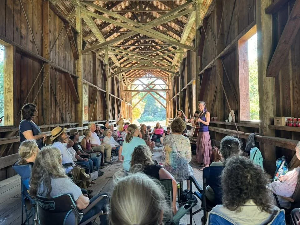 Amanda West leading Bridge Songs community choir inside the Felton Covered Bridge.