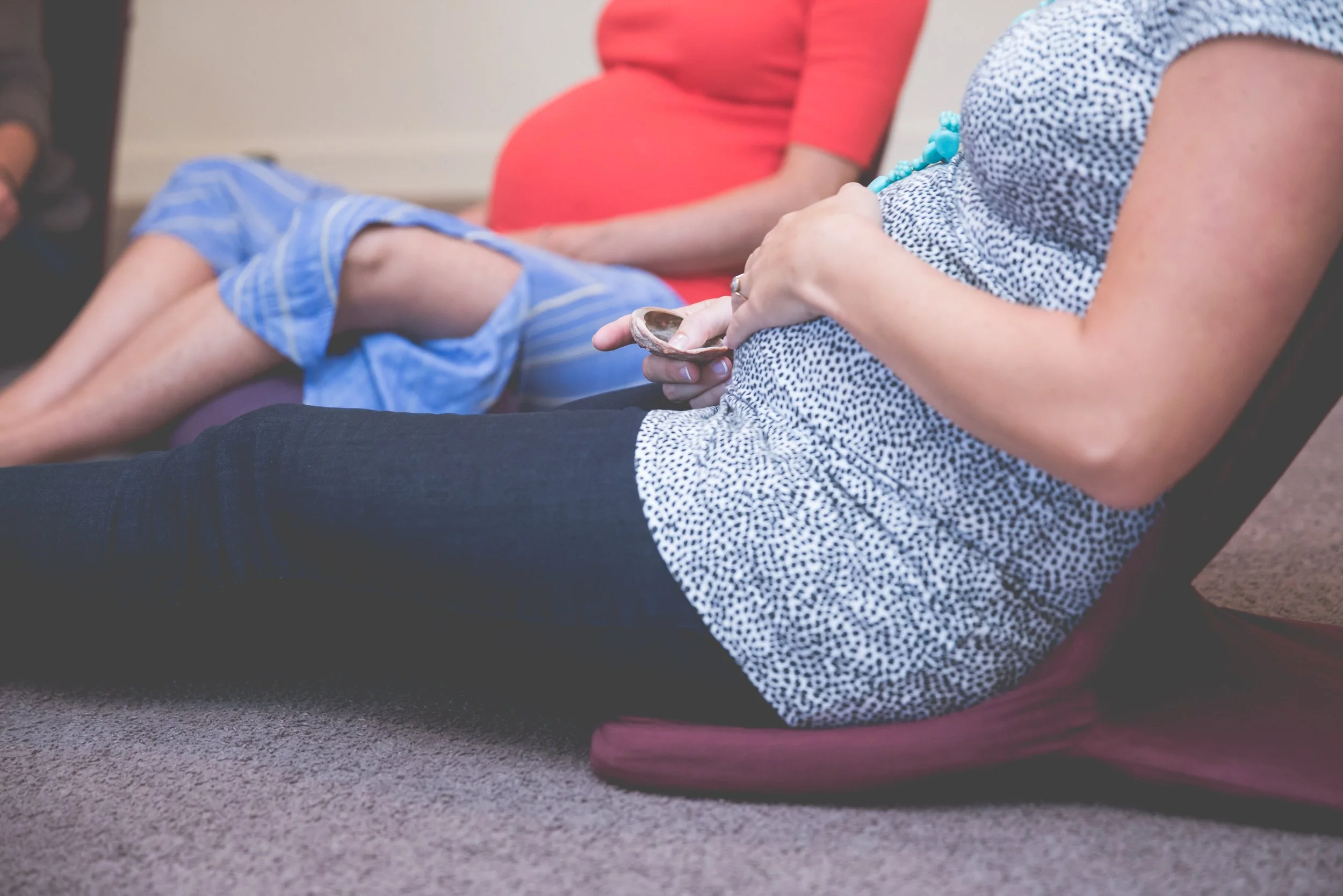 Pregnant participant holding a small percussion instrument during a Womb Song gathering.