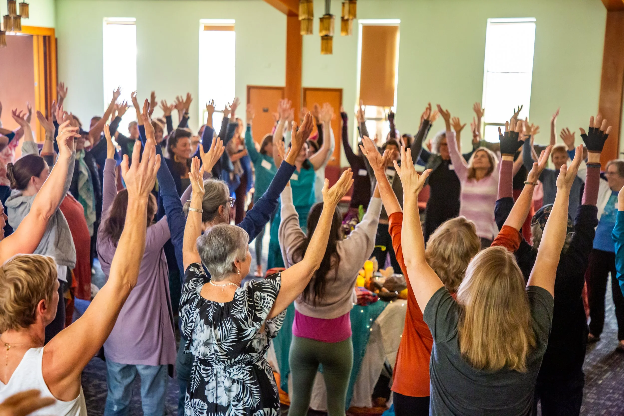Participants singing and raising their arms together at a community singing gathering.