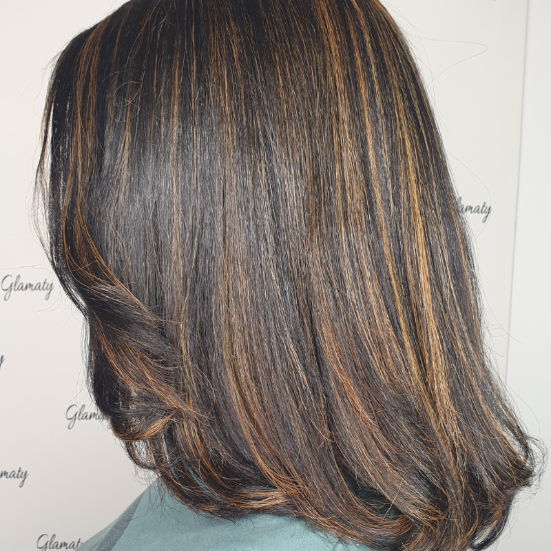 Sint Maarten hair caramel brown highlights, styled straight with some layers.