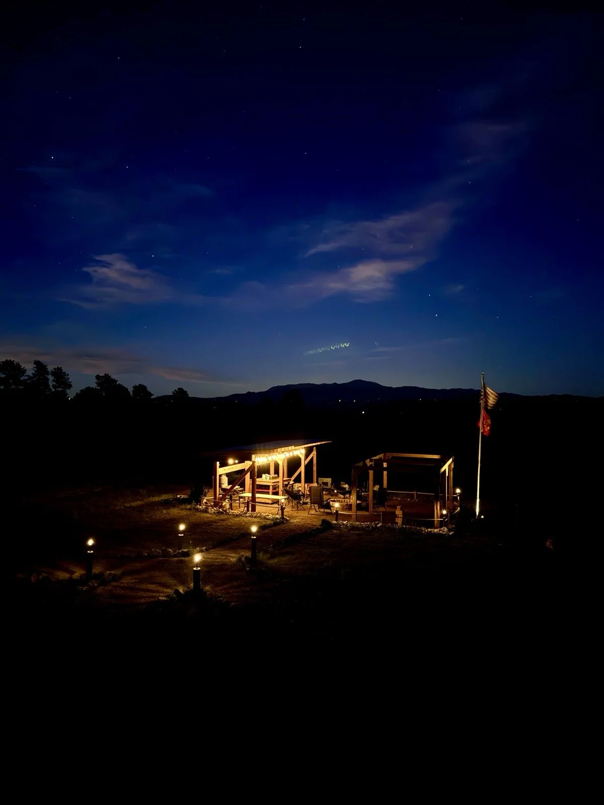 The LZ gathering area and path illuminated beneath the evening sky at Golden Forge.