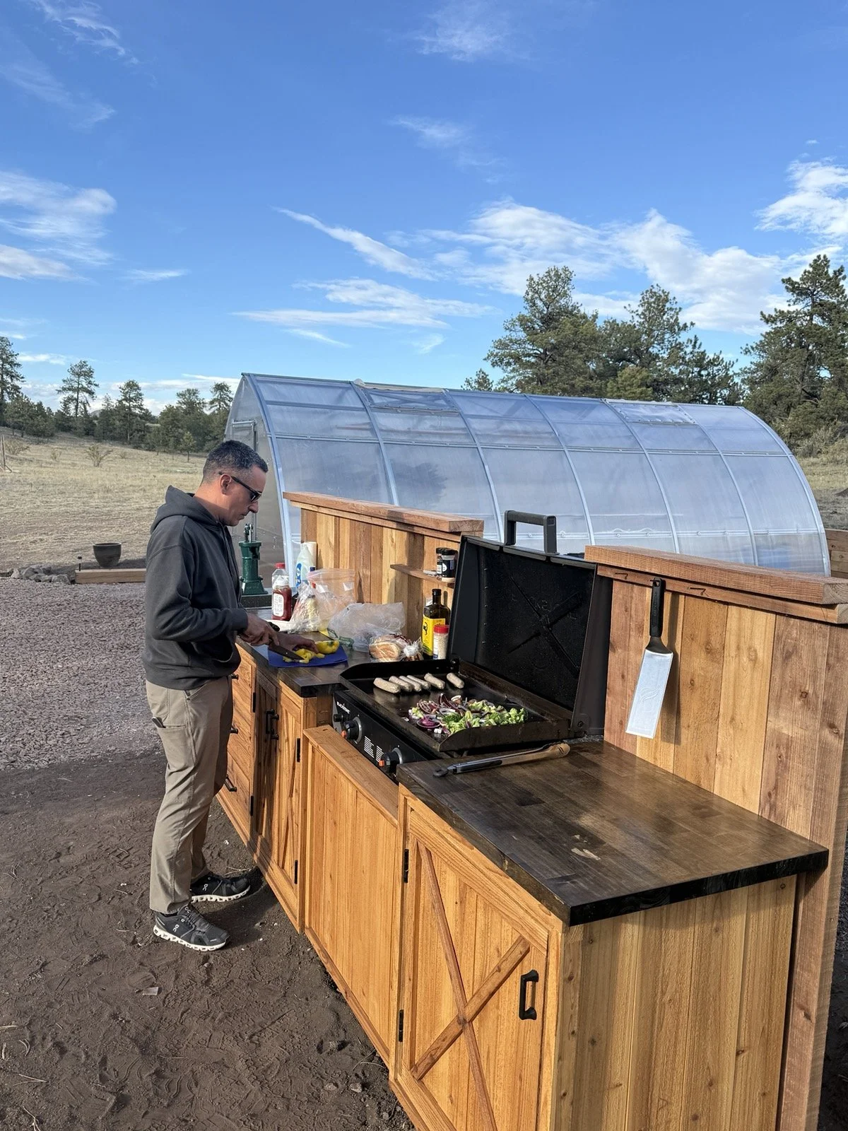 Preparing a shared meal in the outdoor kitchen beside Golden Forge’s greenhouse.