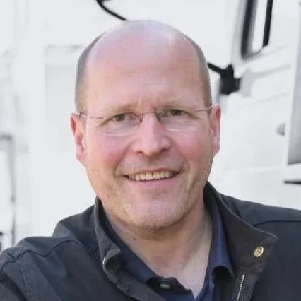 Mann lächelnd vor einem weißen Fahrzeug