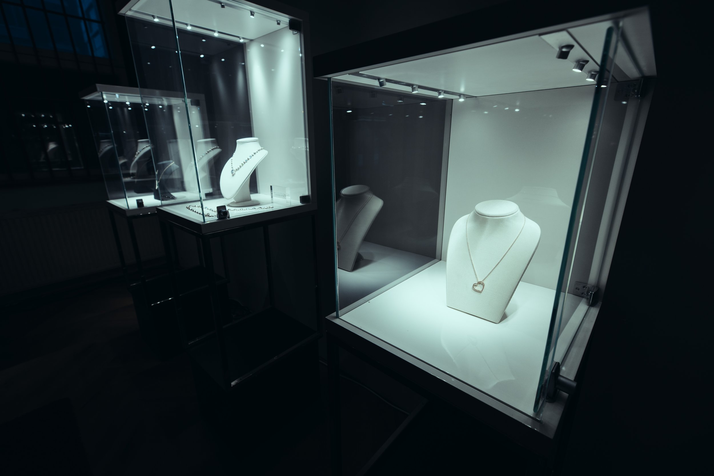 Jewelry display cases showcasing necklaces and earrings in a jewelry store at night.