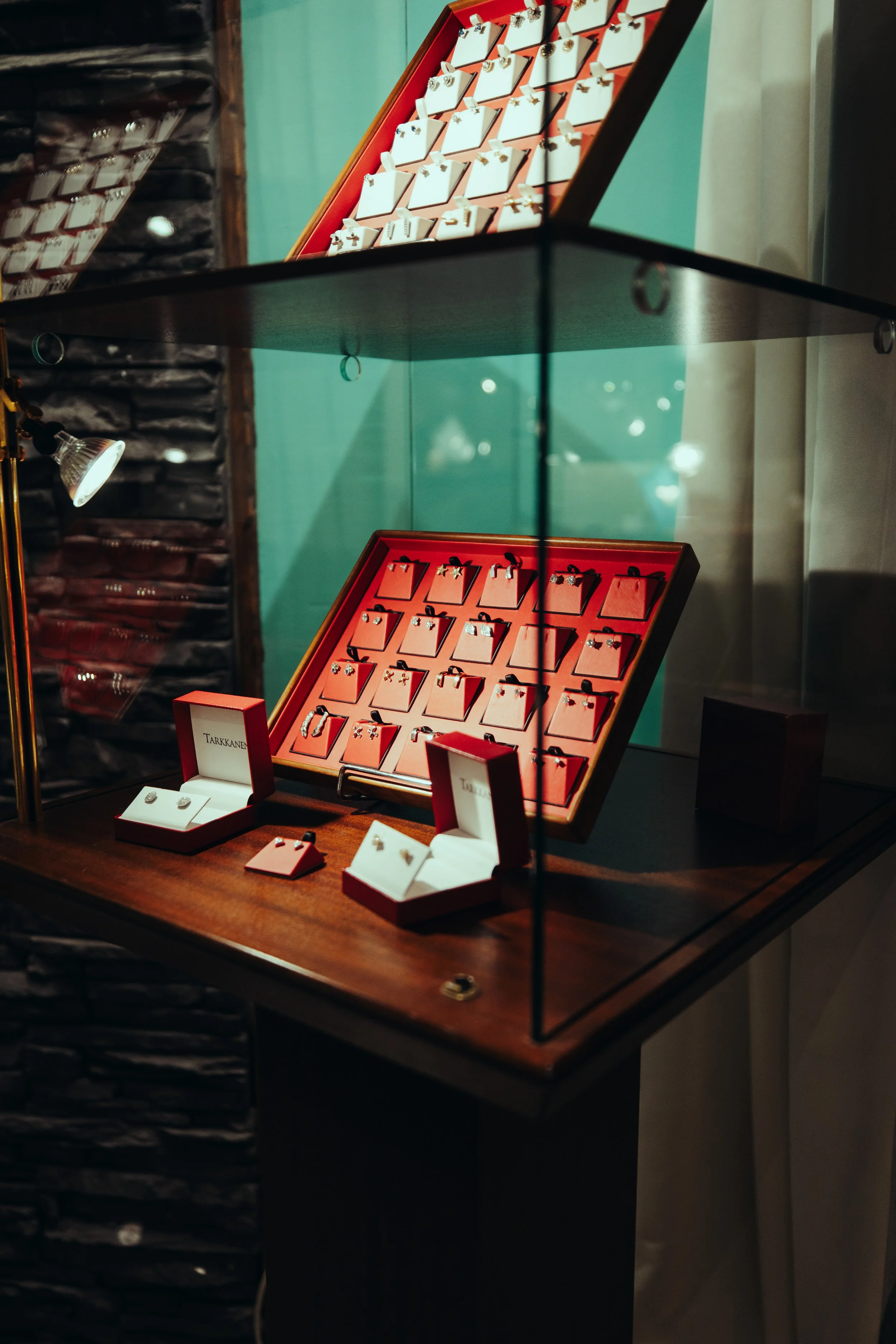 Jewelry display case with rings and earrings, featuring white jewelry on pink backgrounds in a glass cabinet.