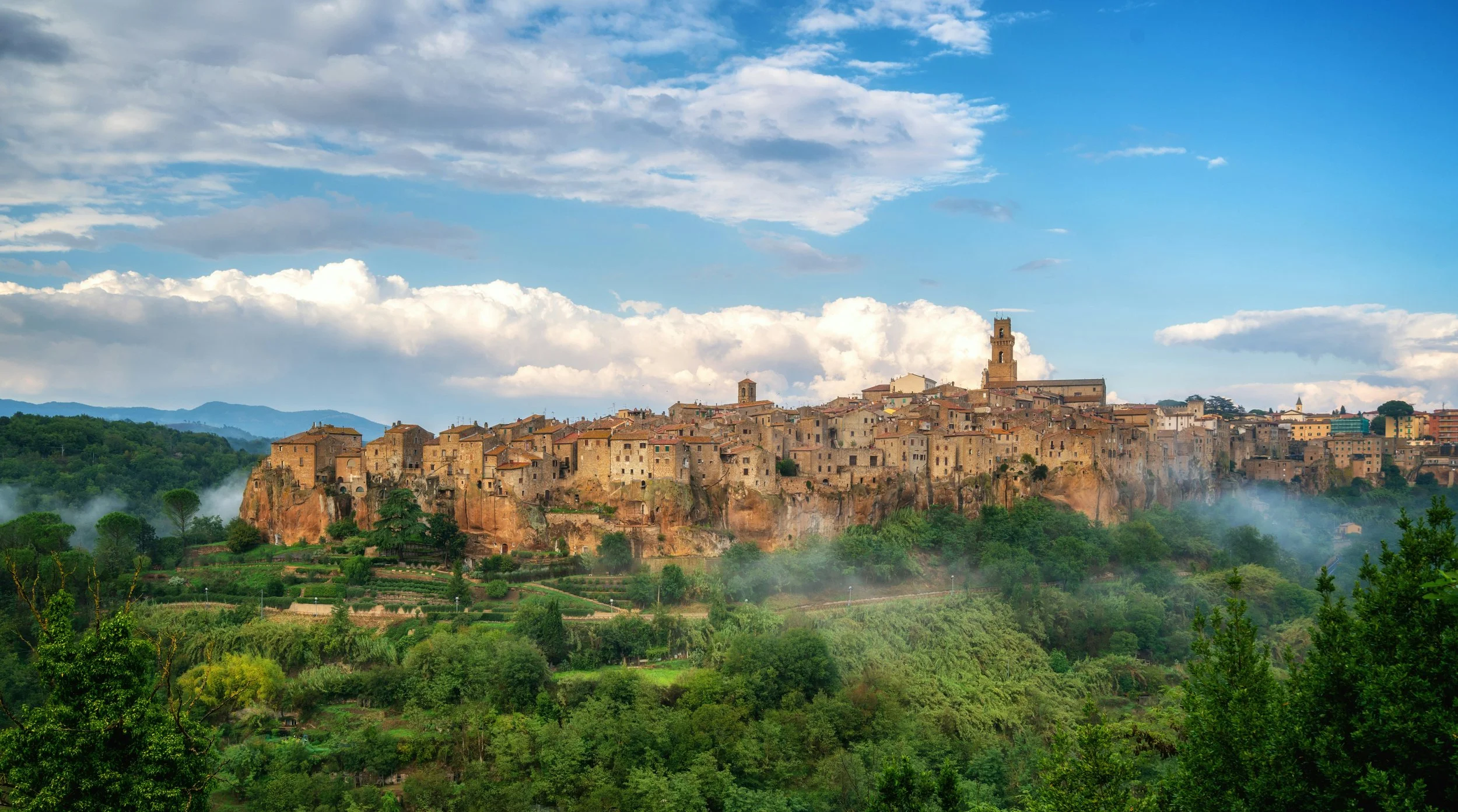 Medieval hilltop village of Pitigliano in southern Tuscany perched on a volcanic tufa cliff surrounded by green hills and morning mist