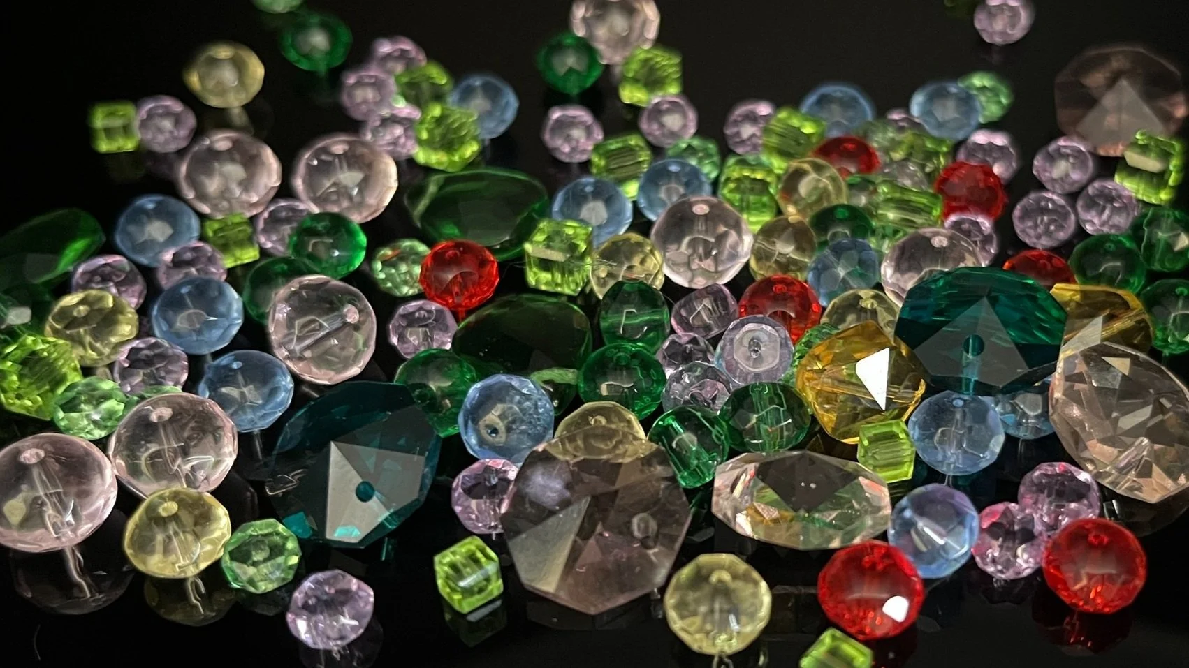 Colorful scattered rhinestones and beads on a dark surface.