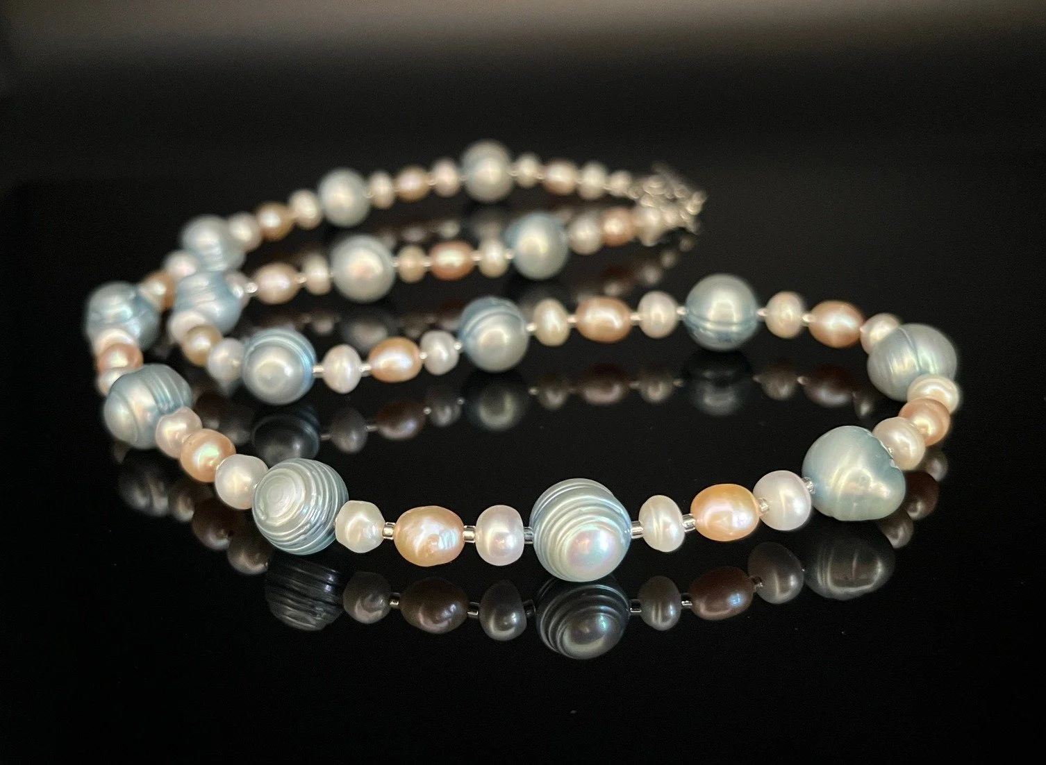 Silver necklace with large crystal pendant against a black background.