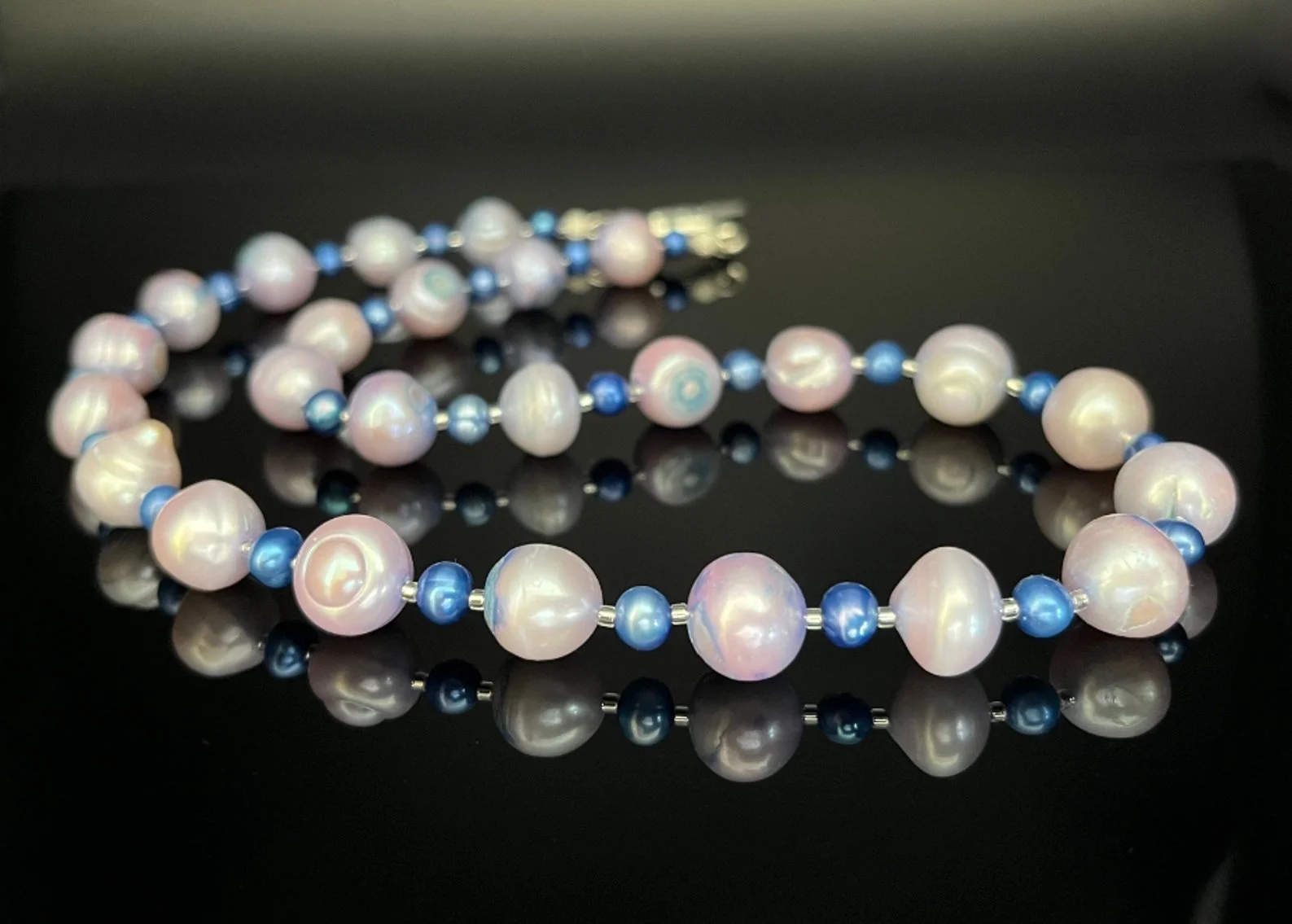 Silver chain necklace with a blue crystal pendant on a black background.