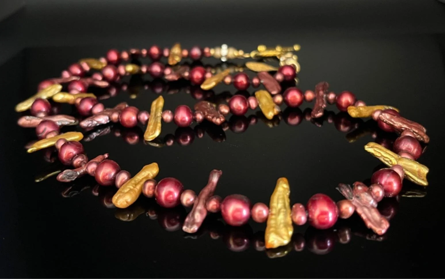 Gold chain necklace with a large red and clear faceted pendant and a small gold owl charm