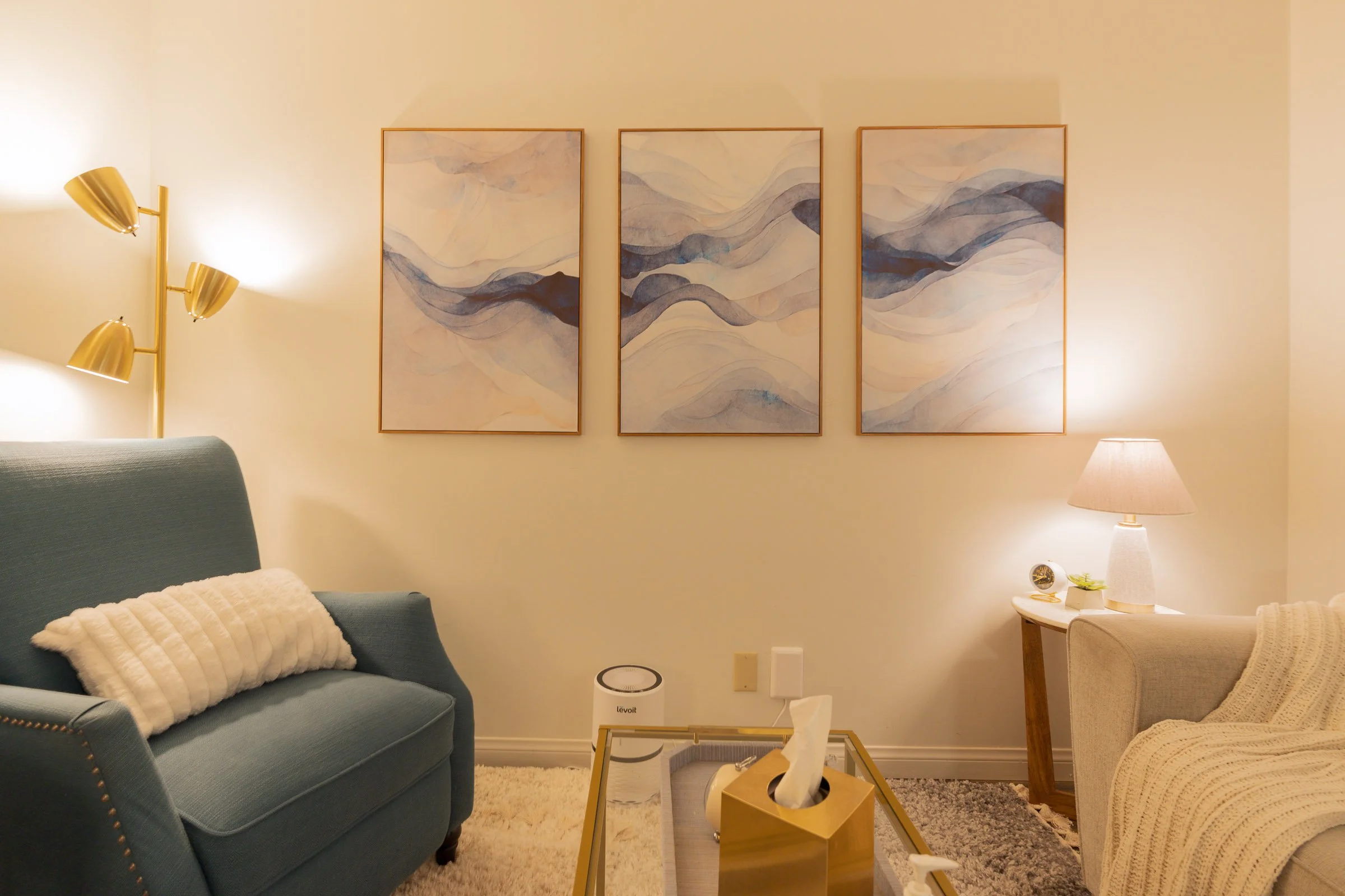 blue chair in a peaceful office with nice lighting and paintings on the wall