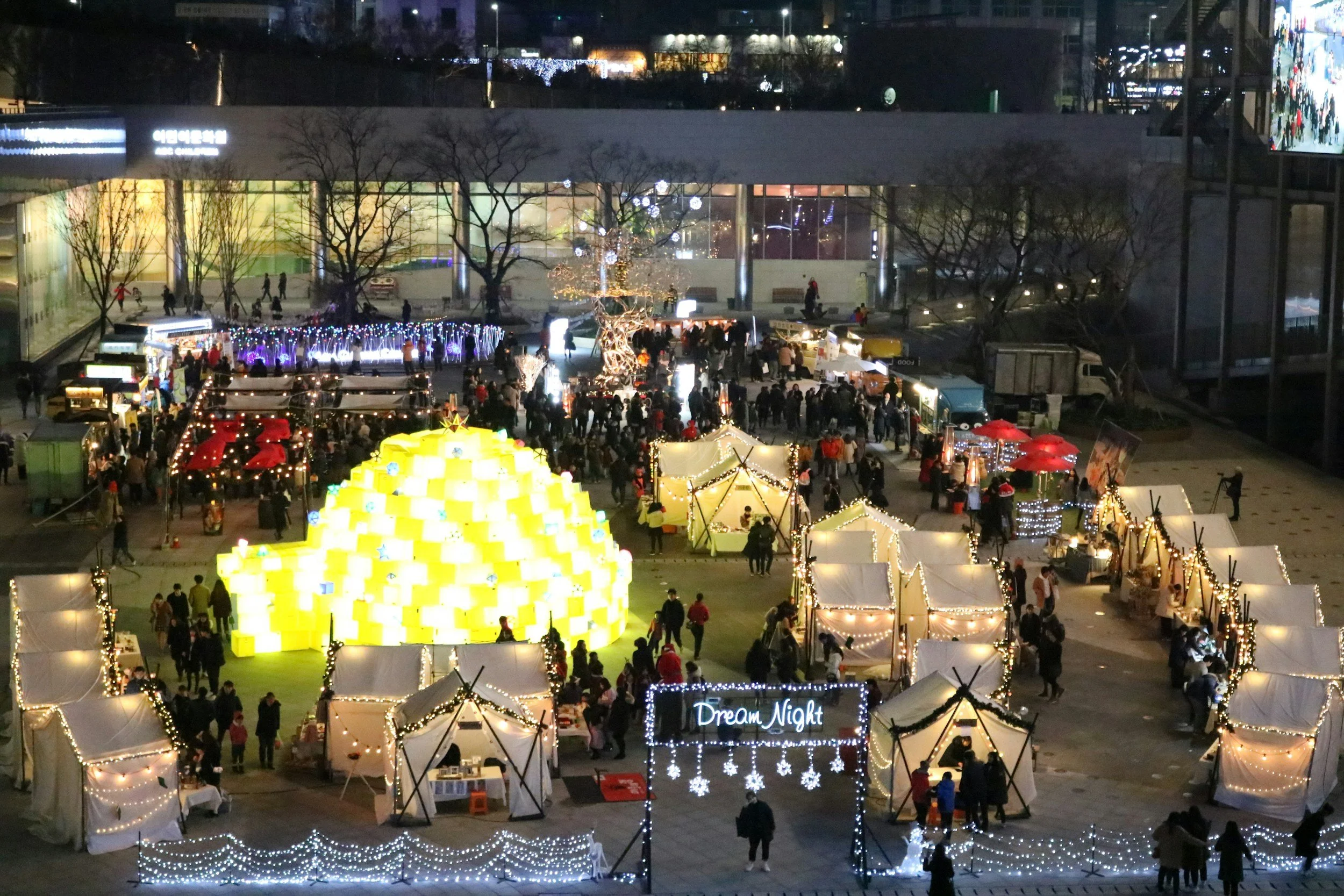An arial view photo of a night market with food vendors and different booths with people mingling around.