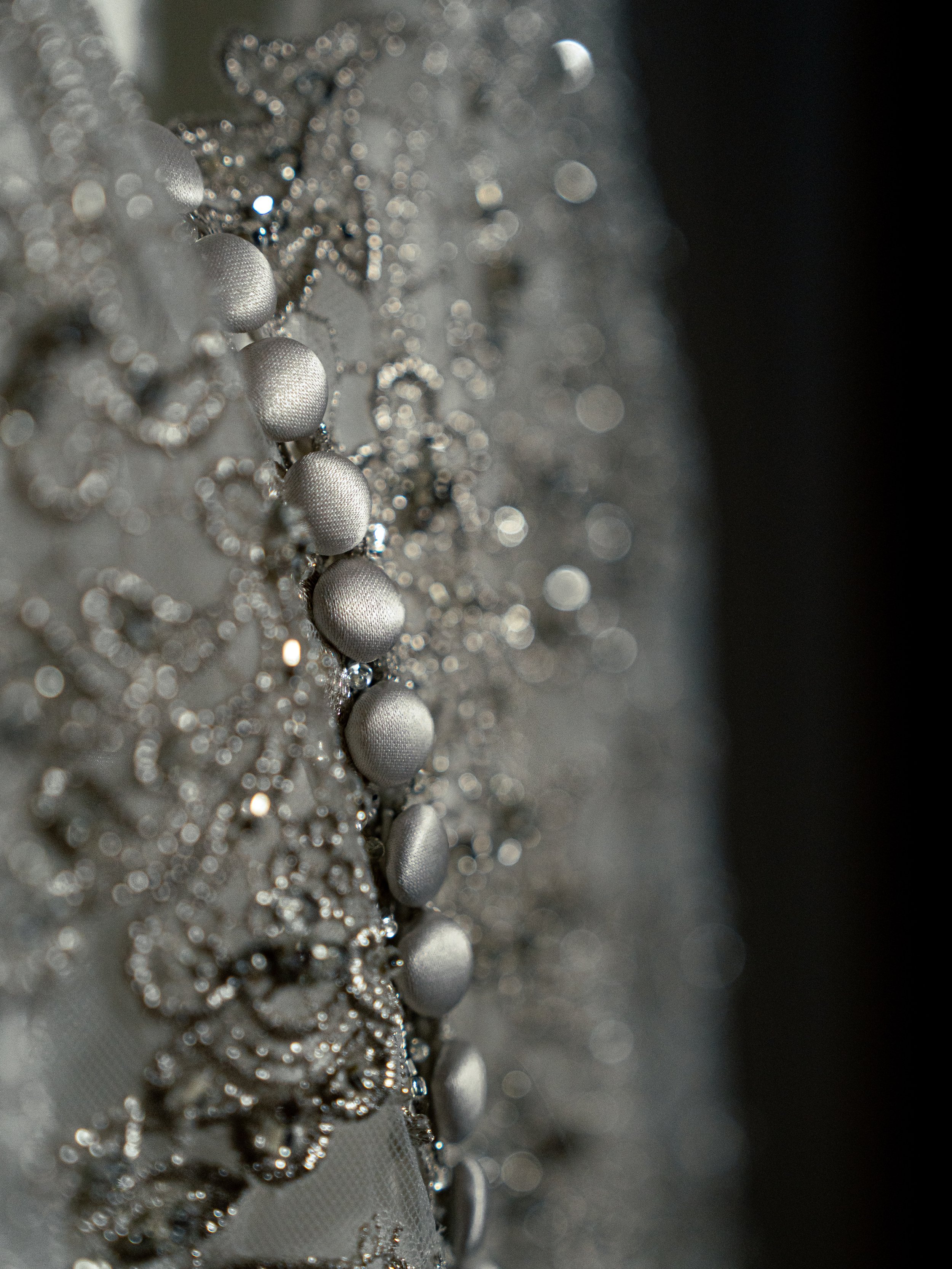 Elegant wedding dress, macro photography, wedding, lace, details, cinematic editing, moody lighting.