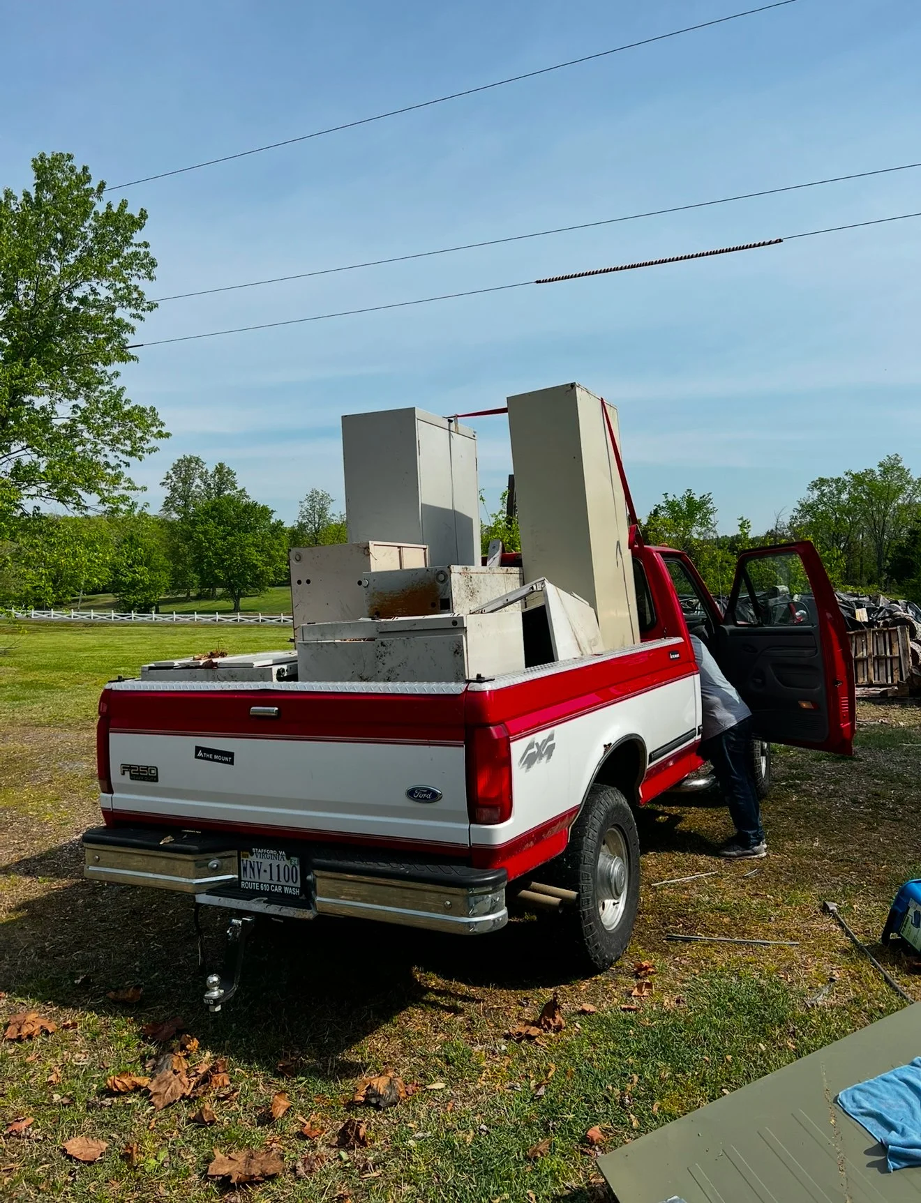 Pickup truck with debris and furniture being loaded with a person leaning into the open passenger door.