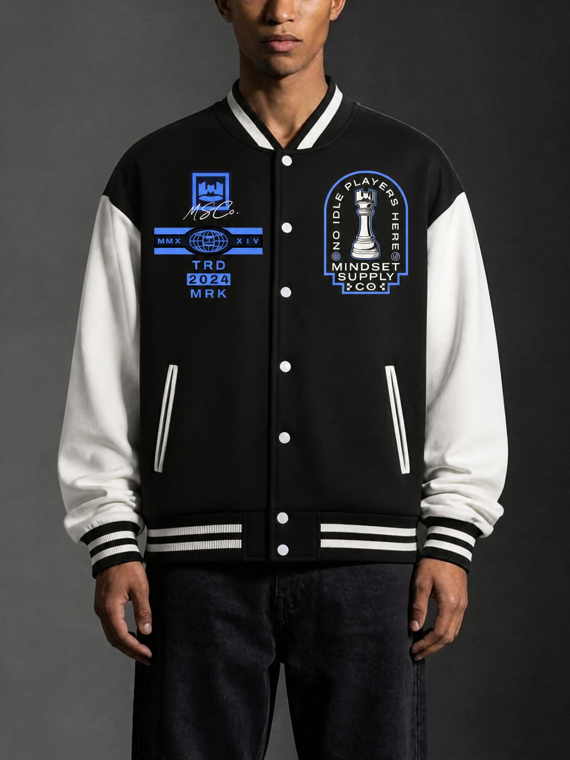 Person wearing a black and white varsity jacket with various patches and logos, standing against a dark background.