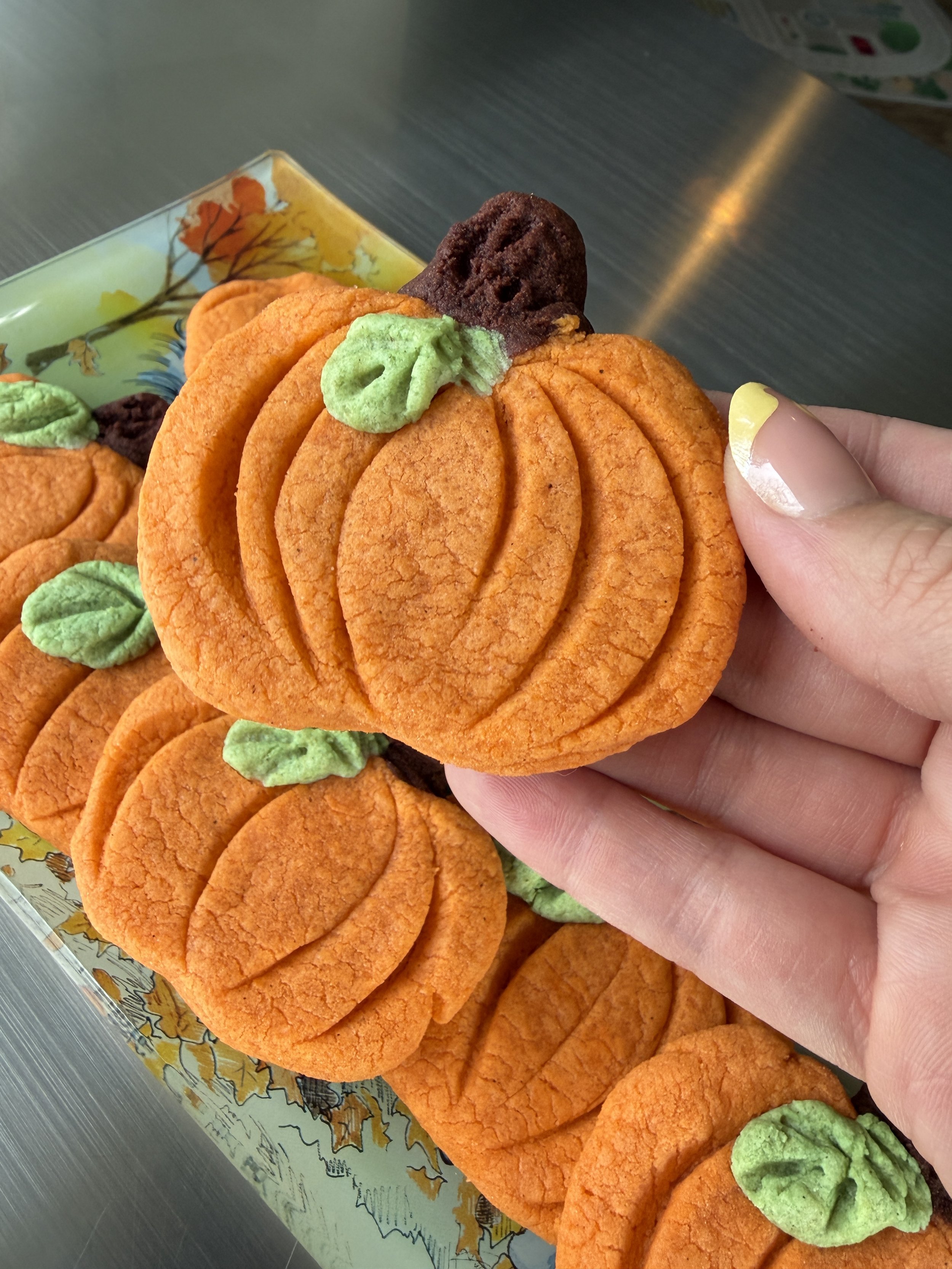 Orange pumpkin cookies with green leaf detail and brown stem.