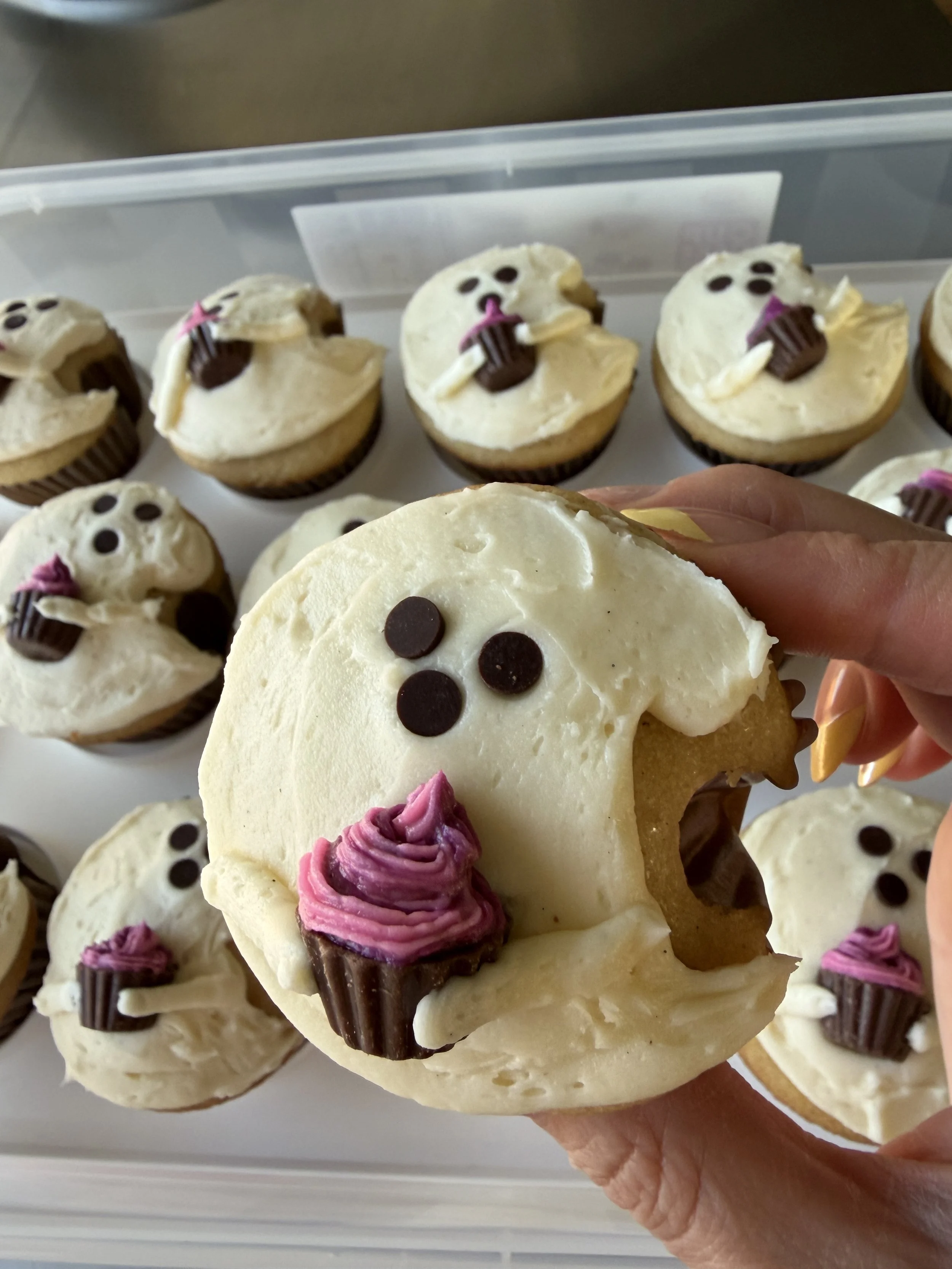 Cupcake shaped like a ghost holding a cupcake with pink buttercream.