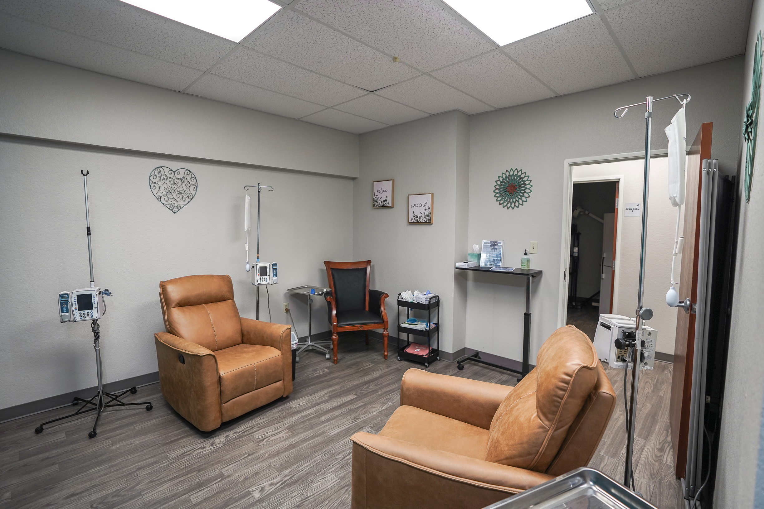 Hospital patient room with medical equipment, chairs, and wall decorations.
