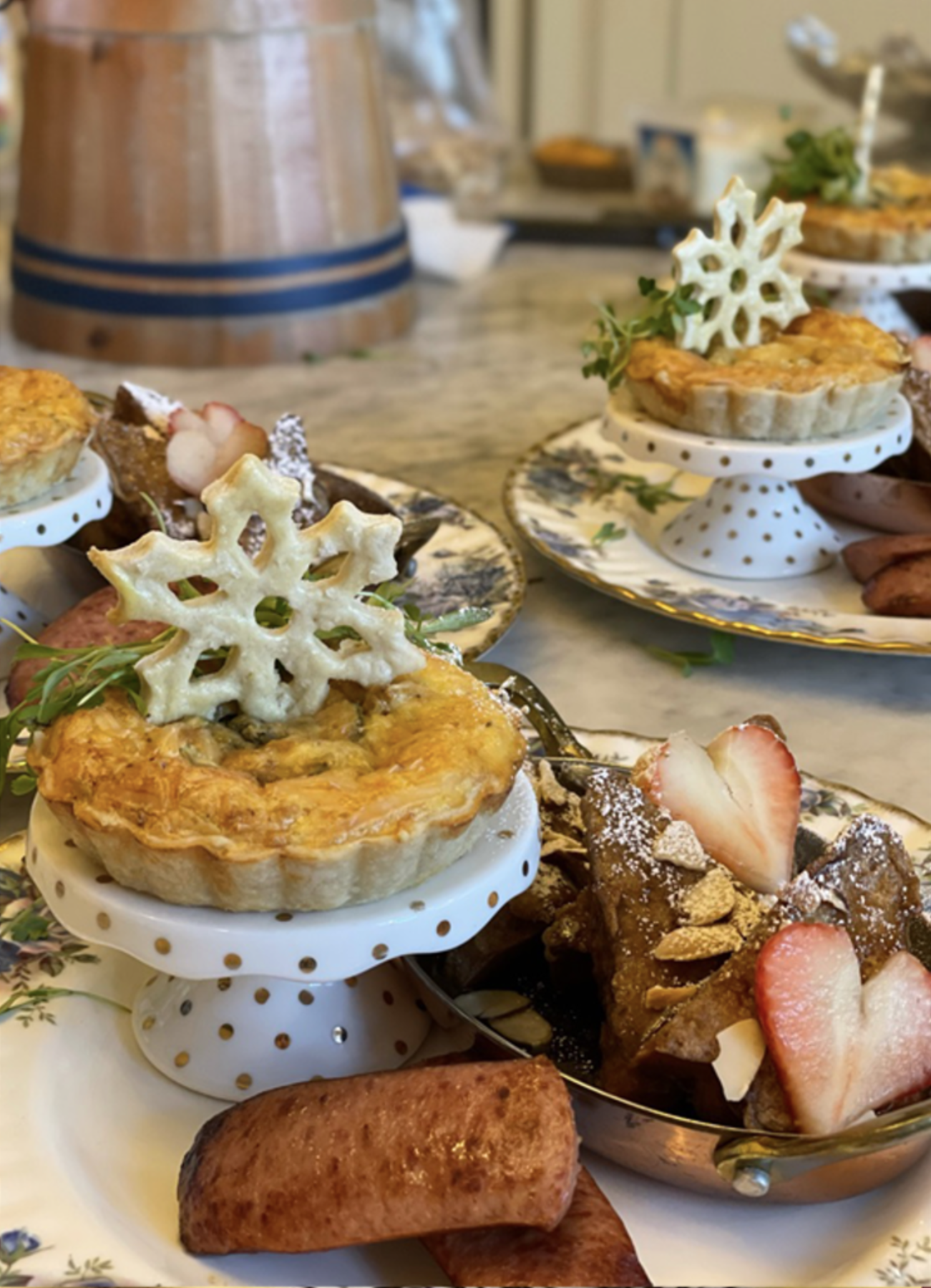 Breakfast featuring mini chicken pot pies topped with snowflake-shaped crackers, strawberry-topped sticky toffee pudding with almonds, a cinnamon roll, and chicken sausage.