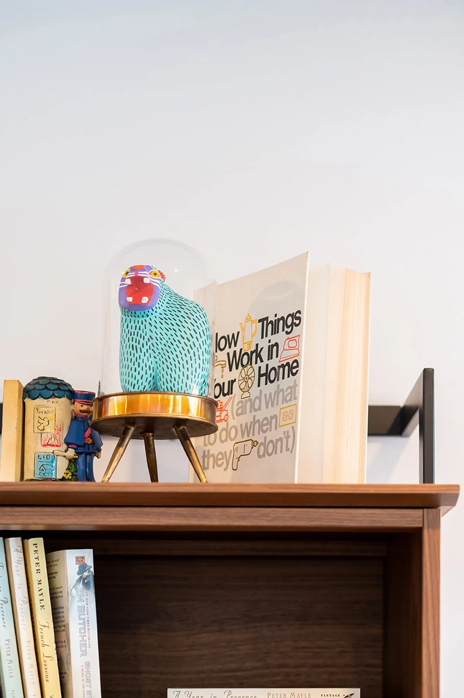 Decorative shelf display with a colorful toy bear inside a glass dome, a small figurine, books, and a sign about household tasks. Seattle, Capitol Hill, Remodel.