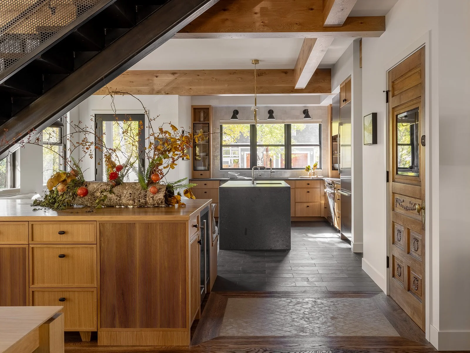 Kitchen with wooden cabinets, black countertop island, and large windows; decorated with autumnal centerpiece of branches and apples. Bozeman, Montana, Remodel.