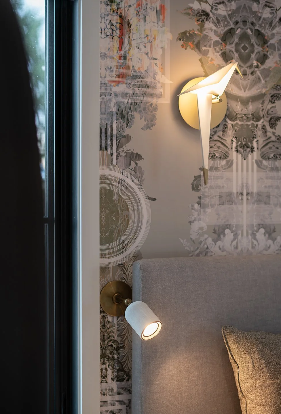 Interior of a modern bedroom corner with a gray upholstered headboard, a fabric pillow, and artistic wall decor. Seattle, Capitol Hill, Remodel.