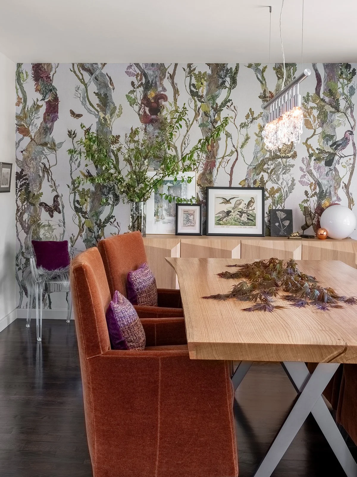 A dining room with a wooden table, rust-colored velvet chairs with decorative pillows,  a wallpaper with a nature scene including trees, birds, and butterflies.  Seattle, Mecer Island, Remodel.
