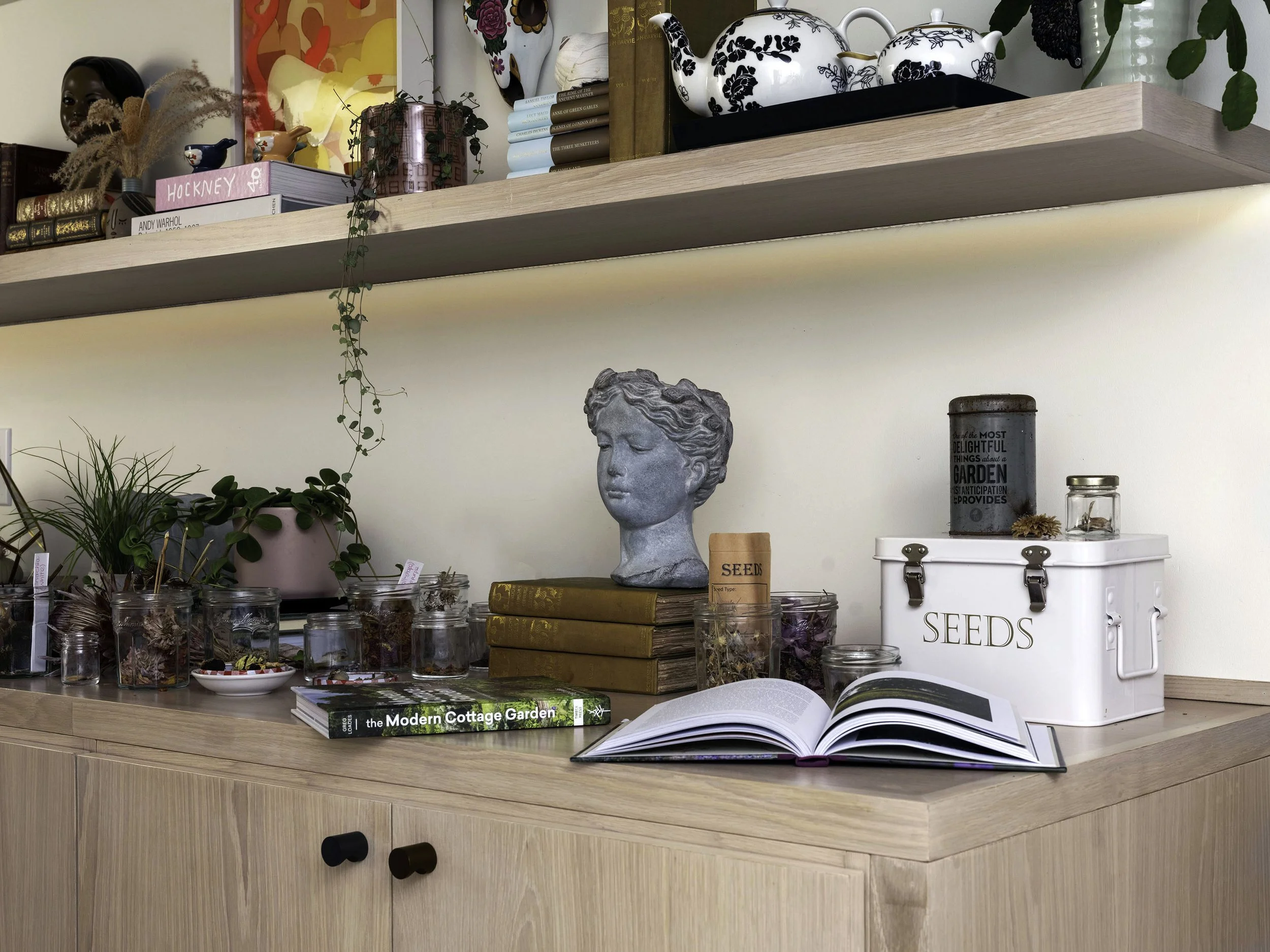 A wooden sideboard with potted plants, jars of dried flowers, an open book. Seattle, Queen Anne, Basement, Remodel.