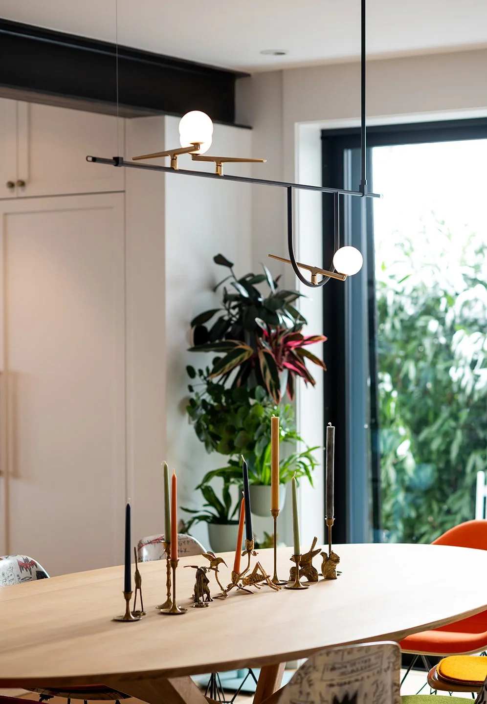 Modern dining room with a wooden table, colorful candles, and decorative animal figures as a centerpiece. A geometric chandelier. Seattle, Capitol Hill, Remodel.