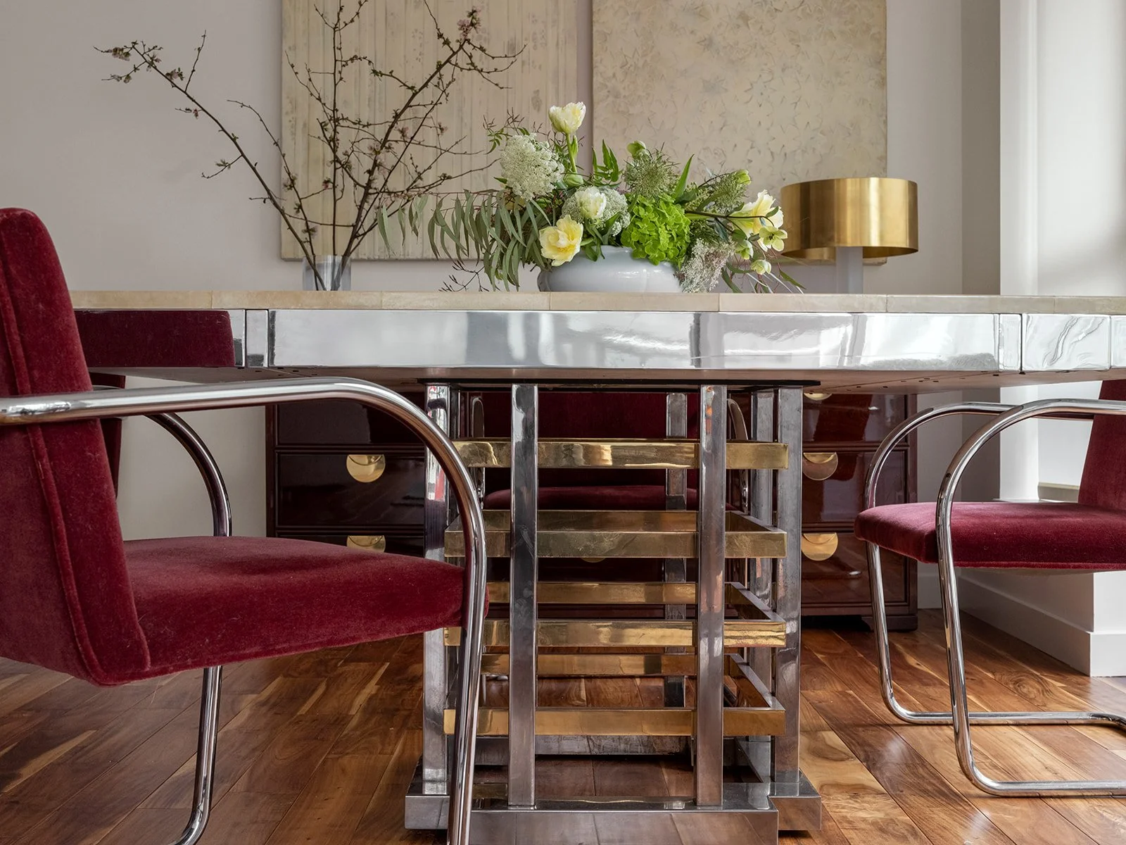 Dining room table with red upholstered chairs, a vase with flowers on the table, and a sideboard in the background. Seattle, Belltown, Condo, Remodel.