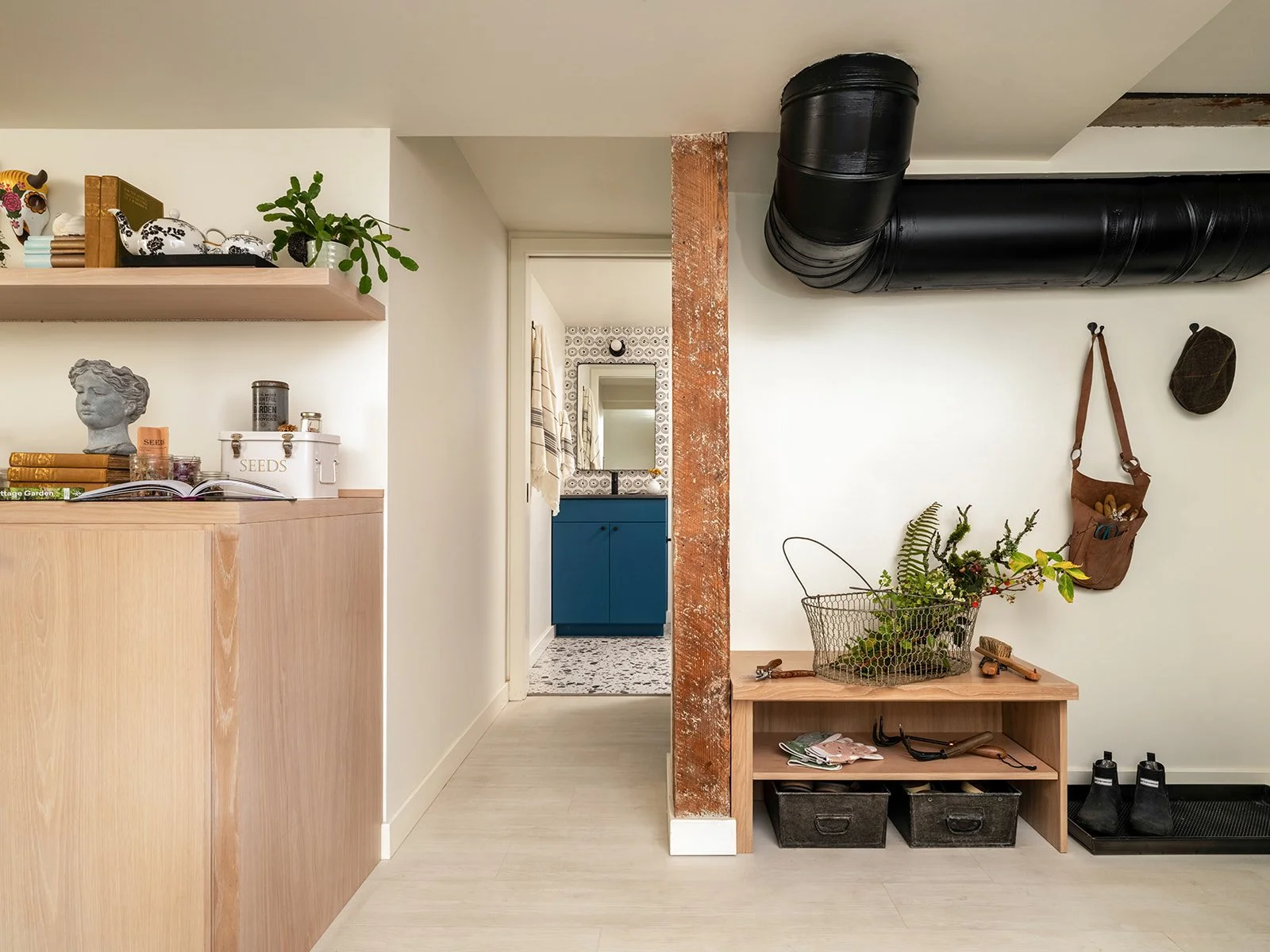 Interior hallway with a small wooden bench holding a wire basket filled with plants, hanging hooks. Seattle, Queen Anne, Basement, Remodel.