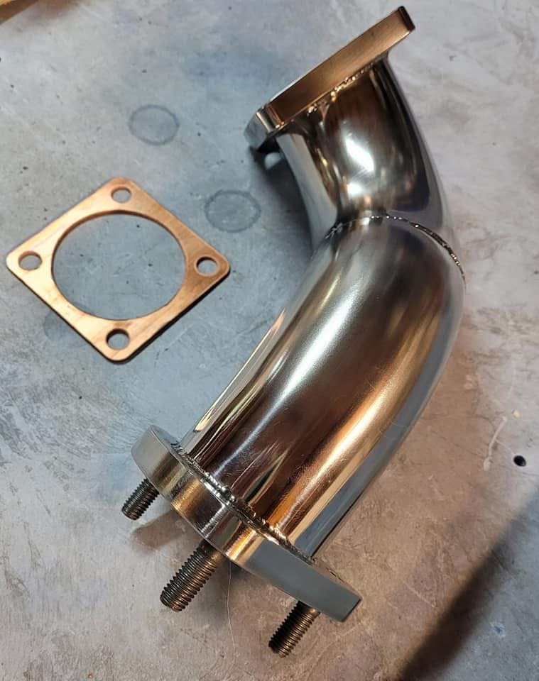 Metallic car exhaust component with flange and gasket on a table